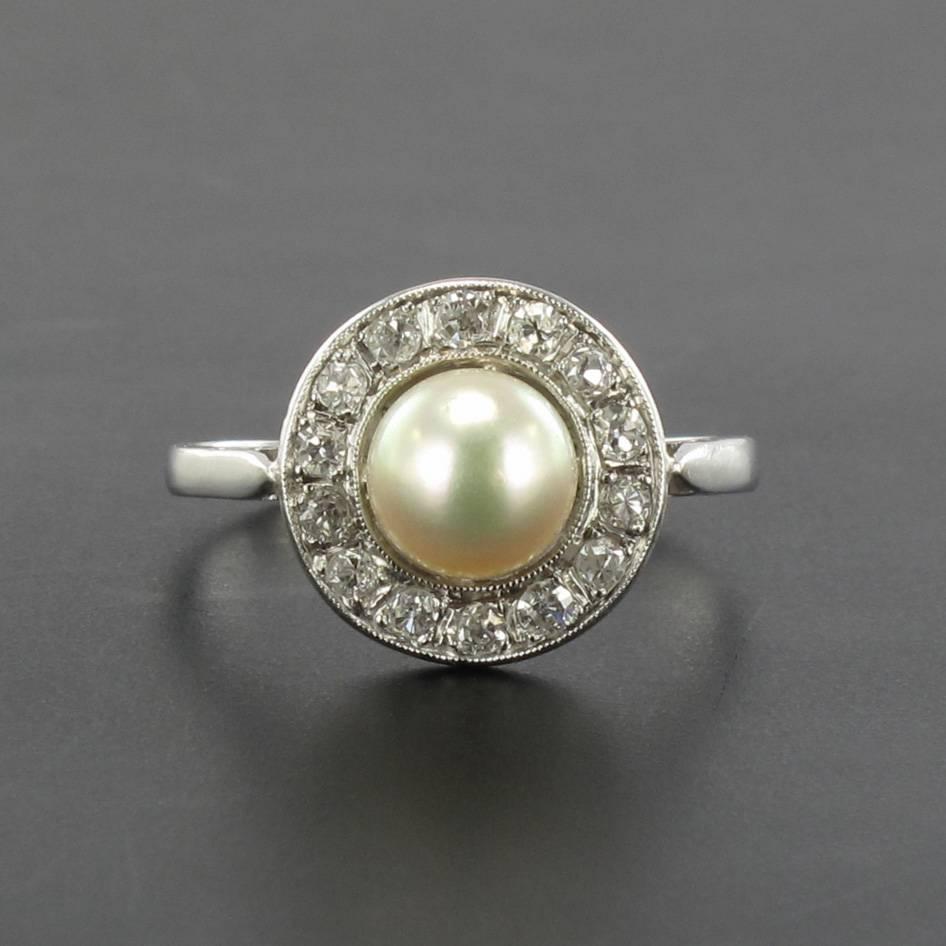 Platinum ring, dog head hallmark.

This magnificent round antique ring is set with a central Japanese cultured white pearl surrounded by 14 antique brilliant cut diamonds in beaded settings in a finely wrought openwork mount. 

Diameter of the