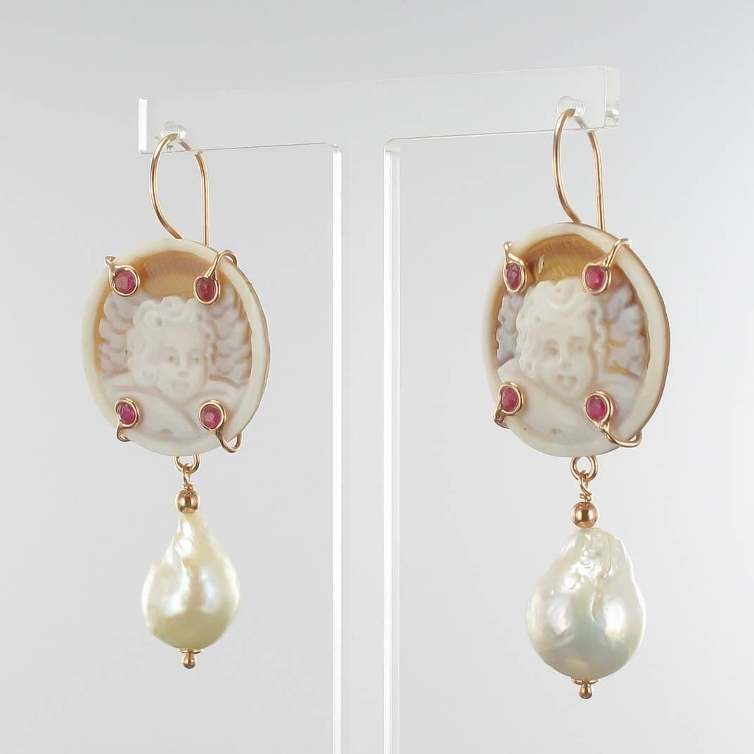For pierced ears.

Pair of earrings in vermeil, silver and rose gold.

Earrings are set with a cameo on shell representing an angelot set with 4 red crystals and which retains in pampille a baroque cultured pearl . The clasp is a gooseneck with