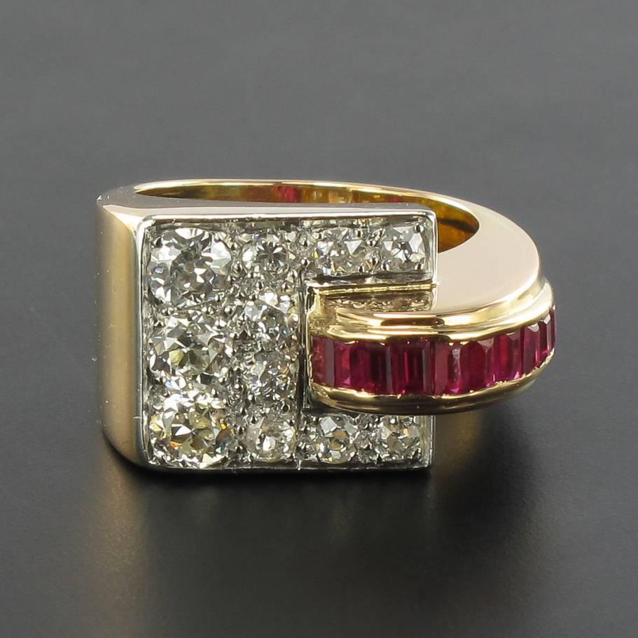 18 carat yellow gold ring.

Splendid geometric shape ring, it is set with an antique brilliant-cut diamond paving. A bridge of calibrated red gems of asymmetrical detachment of the diamond plate.

Total diamond weight: 1 carat approximately.
Height:
