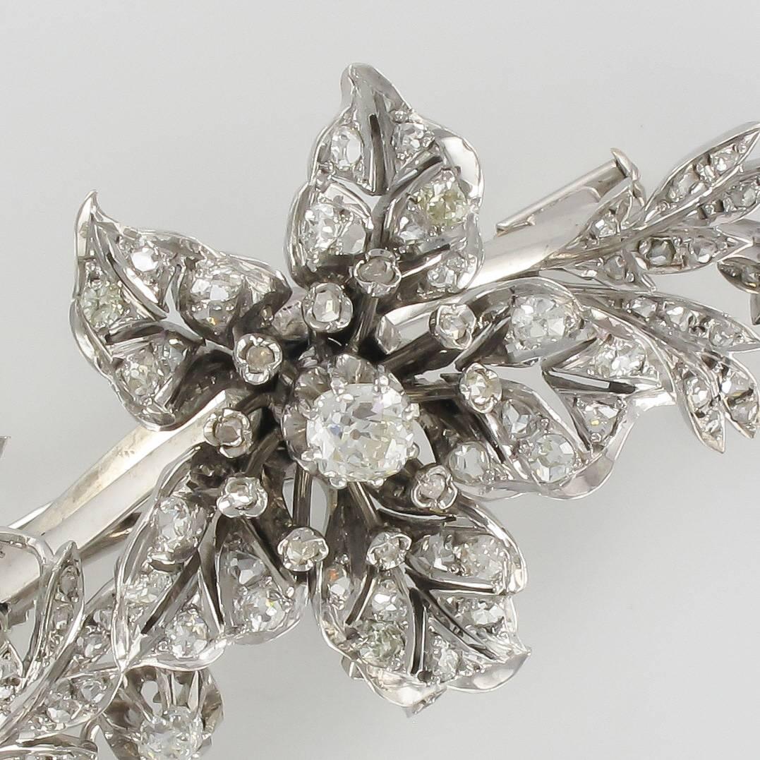 Brooch in 18 carat white gold, head of eagle hallmark and silver, head of boar hallmark.
This splendid antique brooch represents a flower and its branches entirely set with antique brilliant cut diamonds. The flower is mounted on a pivot in order to