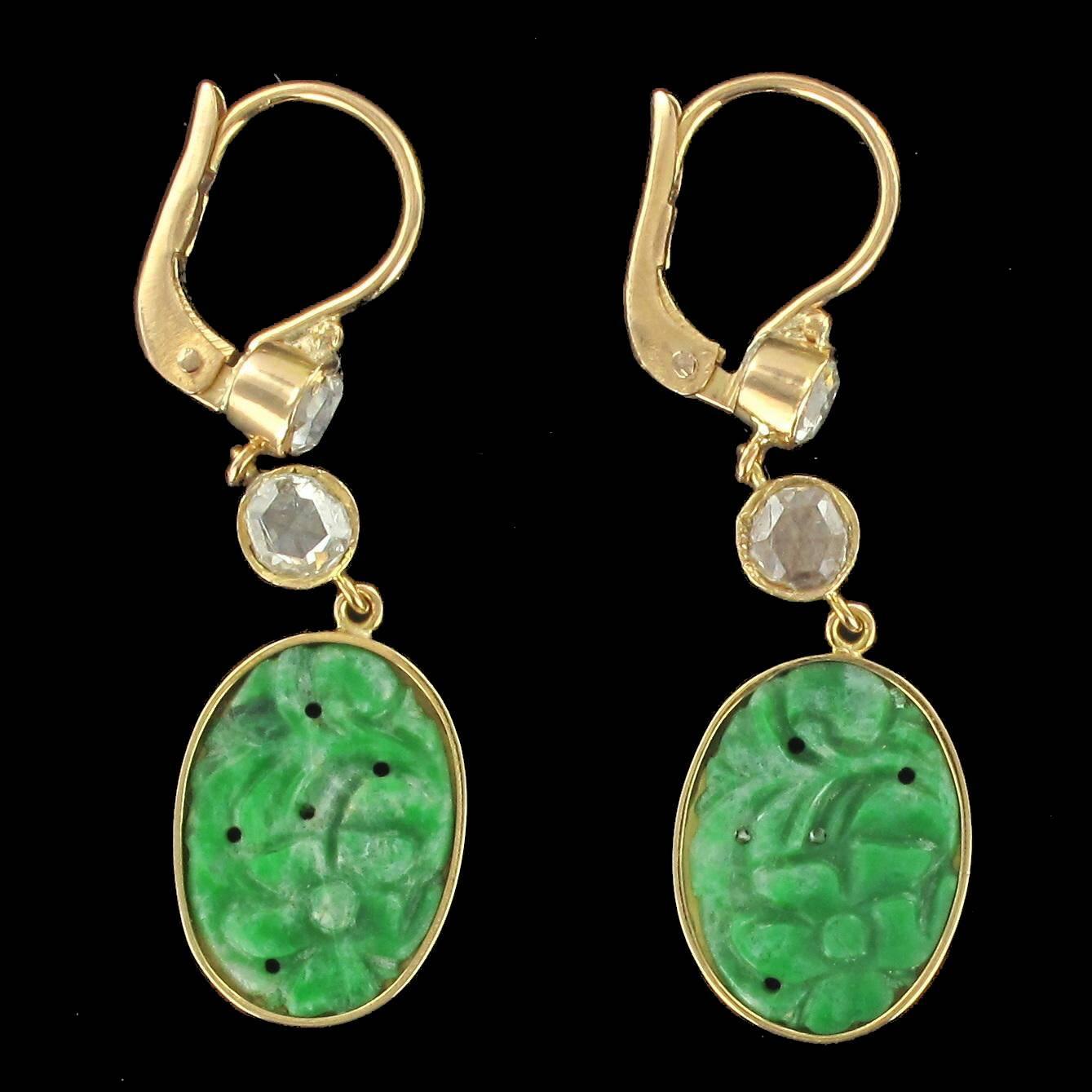 For pierced ears.
Pair of dangle earrings in yellow gold, 18 carats.

Each earring is set with a rose cut bezel set diamond from which is suspended another rose cut bezel set diamond and an oval flower engraved jade plaque encircled with gold.