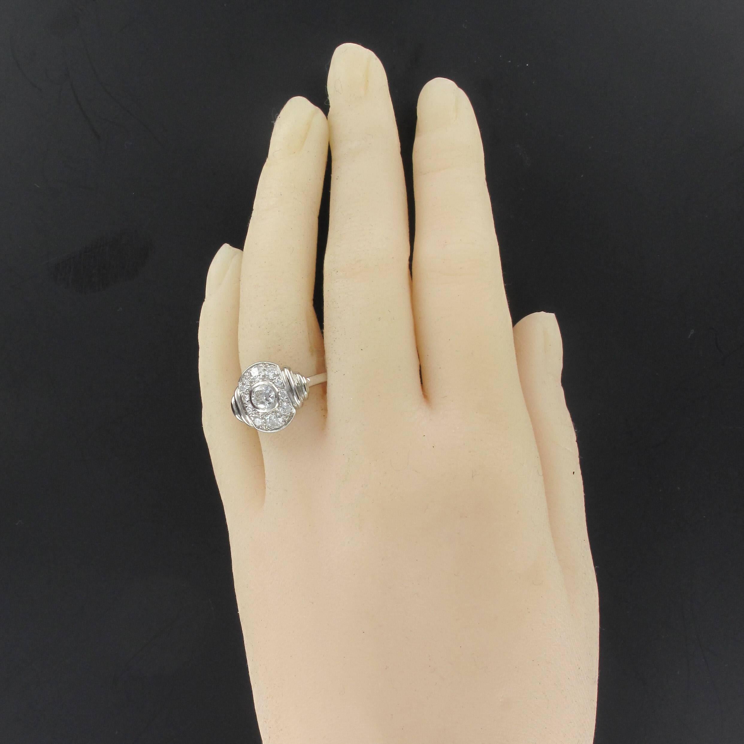 Ring in 18K white gold and platinum.

A splendid oval Art Deco ring set with an antique cut diamond surrounded by numerous small antique cut diamonds. At each shoulder, gadrooning leads to the ring band. 

The center diamond weight: about 0.35