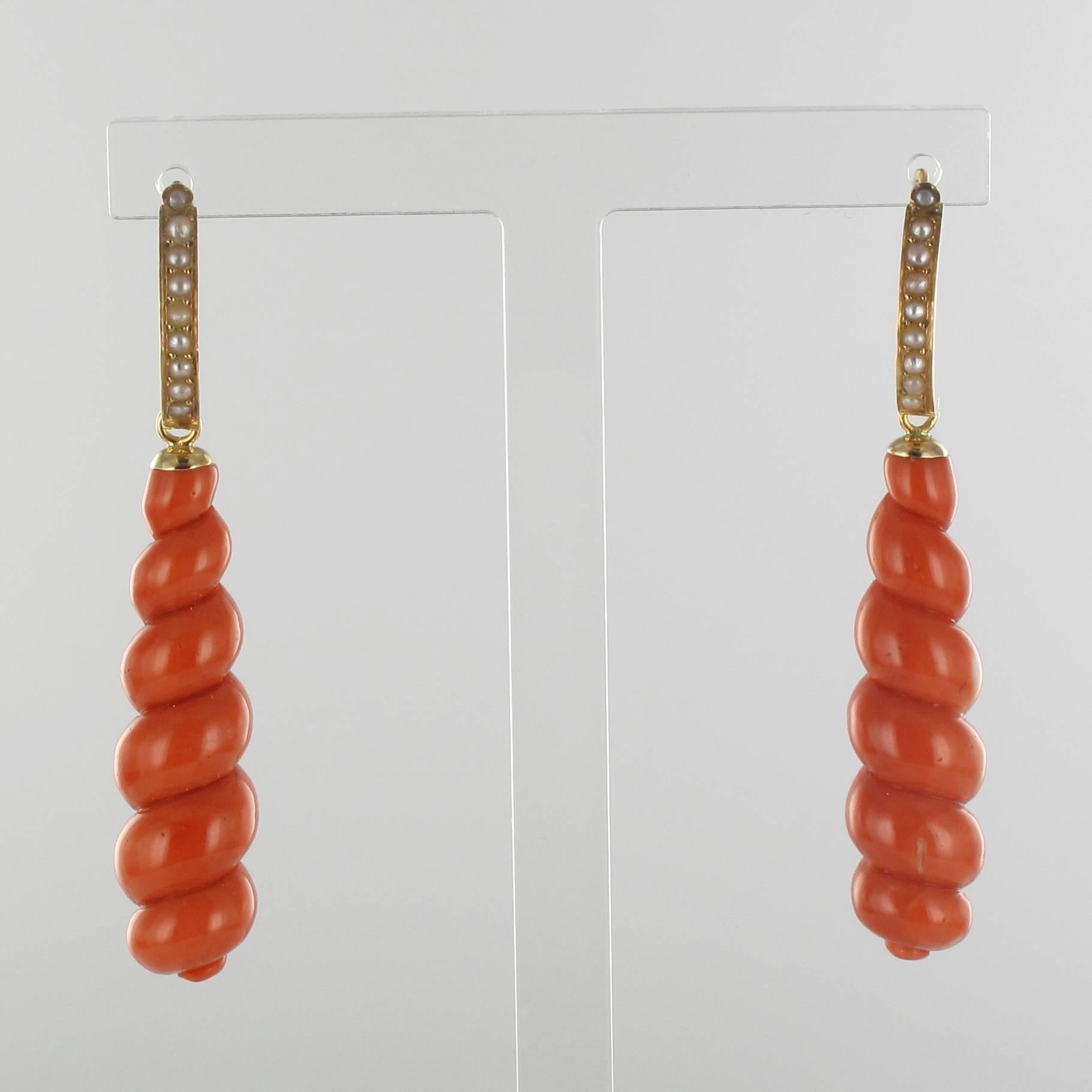 Pair of earrings in 18K rose gold, eagle head hallmark.

In the form of a twist, each antique earring clasp is set in front with a column of half natural pearls. The dangling part is an elegant twist of coral that reaches up to the clasp that