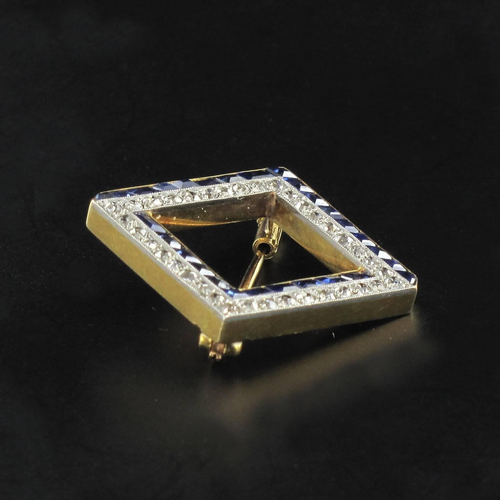 Brooch in 18K yellow gold and platinum, eagle head hallmark.

The sides of this square brooch are set asymmetrically with rows of brilliant cut diamonds and calibrated blue sapphires around an open centre.  The clasp is a pump pin. 

Total