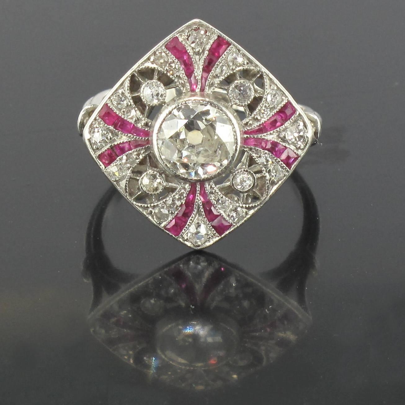 Ring in platinium. 

Splendid rhombic shaped Art Deco ring featuring a central crimped brilliant cut antique diamond. The surrounding openwork is decorated with diamonds and calibrated rubies in curved lines. The beginning of the ring band