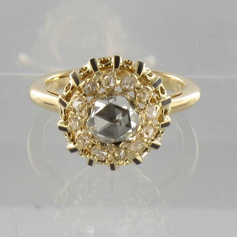 Ring in 18 carat yellow gold, eagle head hallmark. 

A sublime antique ring set with a good sized rose cut diamond surrounded by antique brilliant cut diamonds. These diamonds are set into an openwork bed with surrounding black enamel claws.