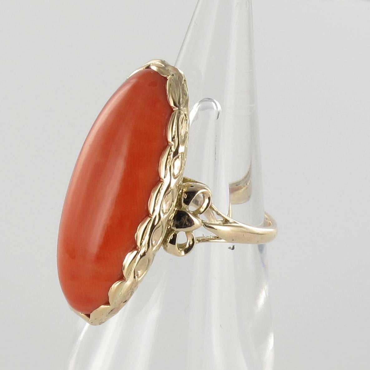 Ring in 14 carat yellow gold. 

Of an elongated form, this sublime gold ring is set with an oval coral cabochon from the Torre del Greco. The entire bed features finely chased gold pleats. The shoulders of the ring are decorated with 2 golden