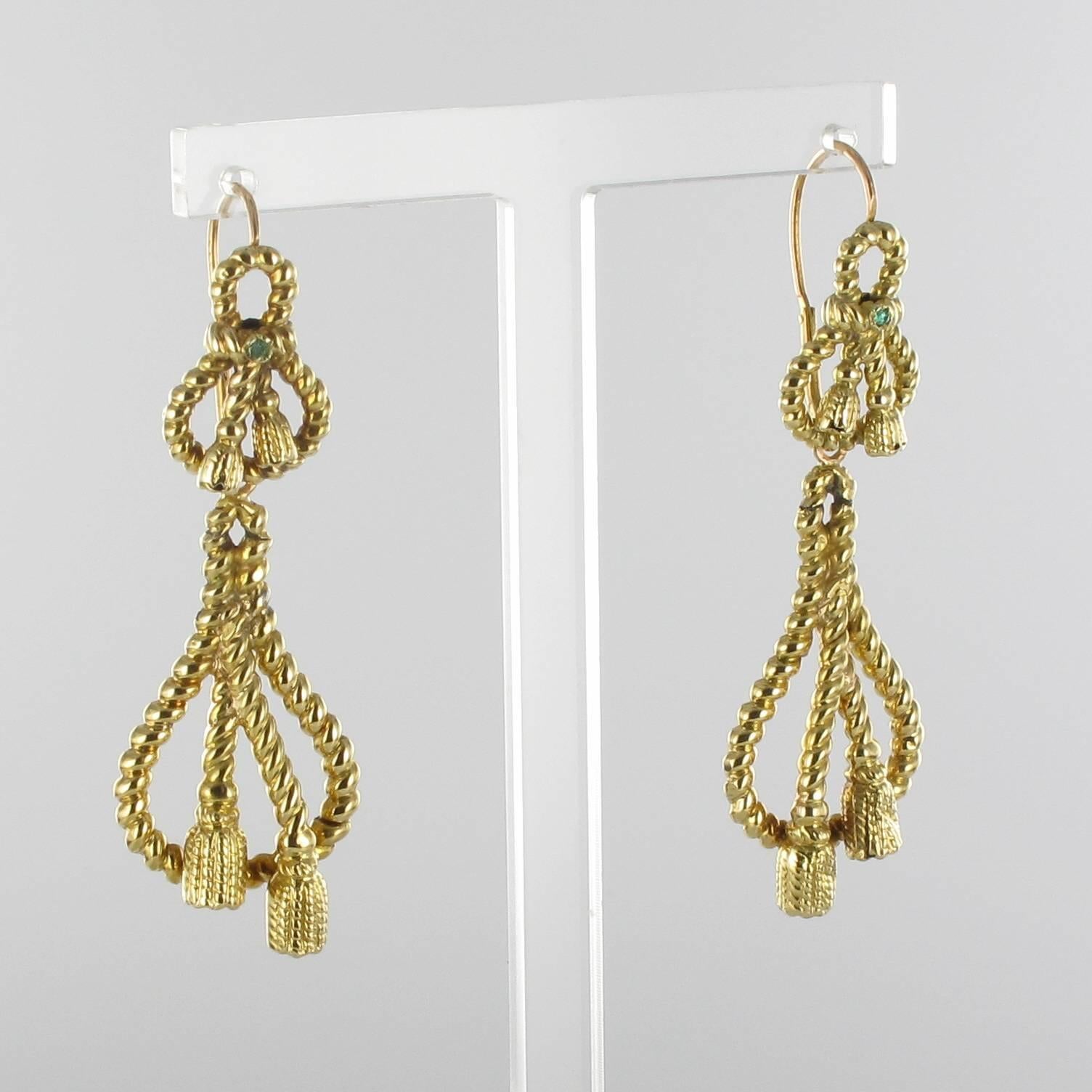 Earrings in 18 carat yellow gold, eagle head hallmark. 
These antique drop earrings are each composed of a coiled gold rope that terminates with golden tassels and feature a round emerald at the centre. These antique earrings hold a pendant with the