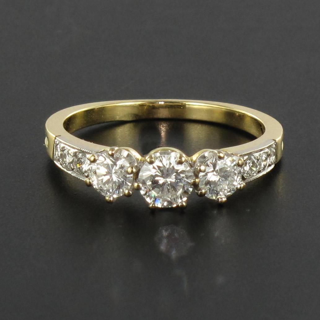 Ring in 18 carat yellow and white gold, eagle head hallmark. 

A trinity ring featuring 3 brilliant cut claw set diamonds shouldered by a row of 3 pave diamonds on each shoulder. 

Total weight of the center diamond : approx 0.40 carat 
Total