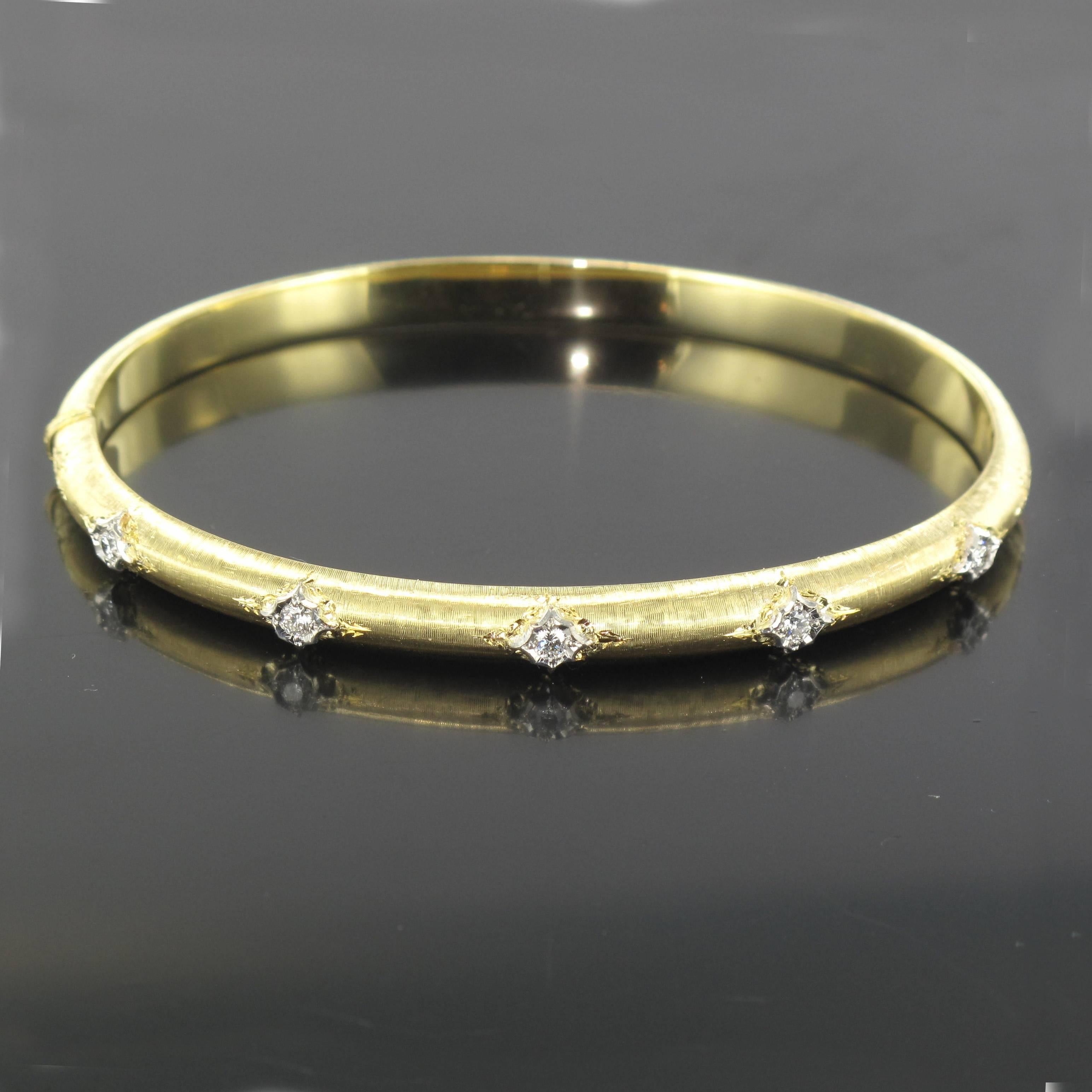Bangle bracelet in 18 carat satin yellow gold.
This lovely oval and rounded bracelet is made from brushed yellow gold that is engraved and set with 5 brilliant cut diamonds. This diamond bracelet opens with a hinge. 
Total diamond weight: about 0.20