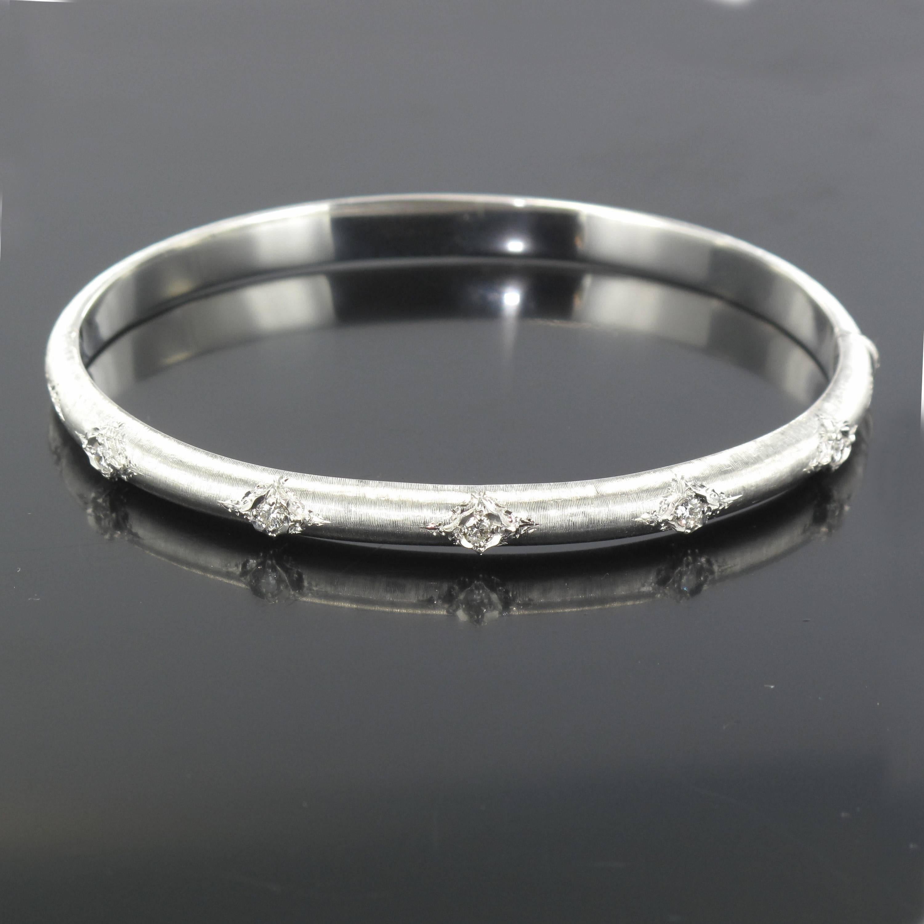 Bangle bracelet in 18 carat satin white gold.
This delightful white gold bangle bracelet is oval and rounded in form. Created in brushed white gold it is engraved and set with 5 brilliant cut diamonds at the front, it opens with a hinge. 
Total