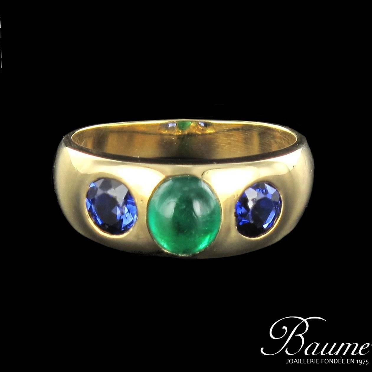 18 carat ellow gold ring, eagle head hallmark.

This rounded ring is set with a central emerald cabochon enhanced by round blue sapphires at each side. 
Total weight of the emerald: 1.44 carat approximately 
Total weight of sapphires: about 1.20