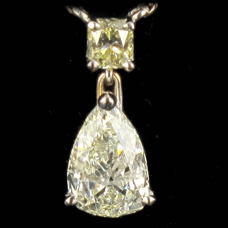 Pendant and chain in 18 carat white gold. 

Featuring a claw set central pear cut diamond with a claw set yellow cushion cut diamond above, the quality of these diamonds is estimated to be of IJ/SI. The necklace chain is textured and enhanced by 7