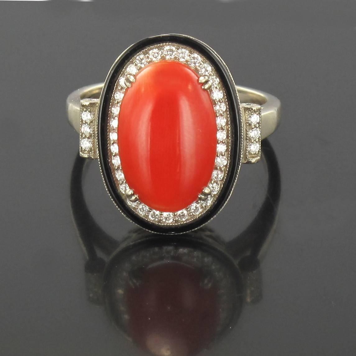 Ring in 18 carat white gold. 

Oval in form, this ring features a central double claw set oval coral cabochon with a halo of diamonds bordered with a circle of onyx. At each side 3 diamonds are set at the beginning of the ring band. 

Total weight