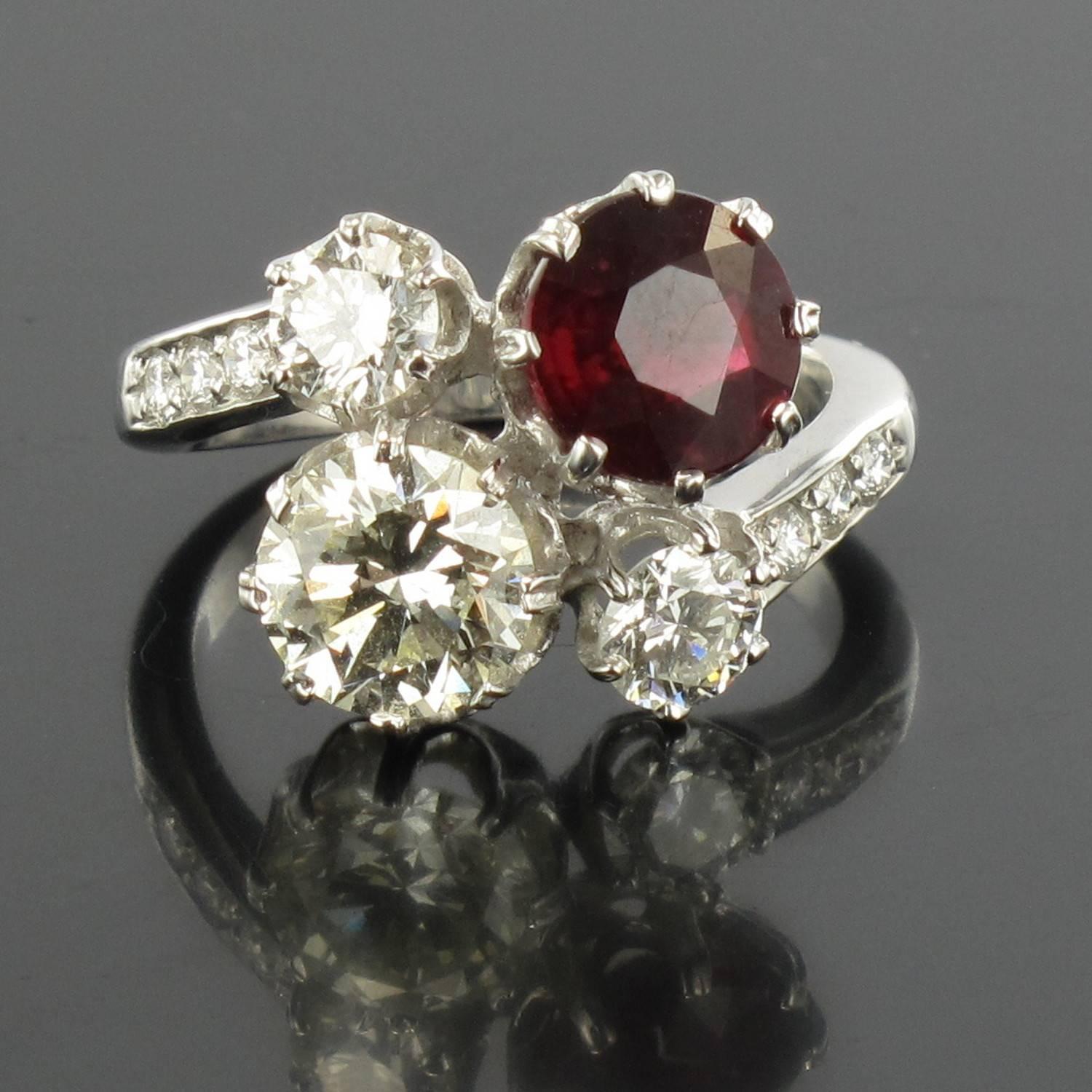 Ring in 18 carat white gold, eagle head hallmark. 

Featuring a claw set round ruby and a brilliant cut diamond, another smaller diamond is set at each side with a further 3 small diamonds leading into the ring band on each side. 

Ruby Weight :
