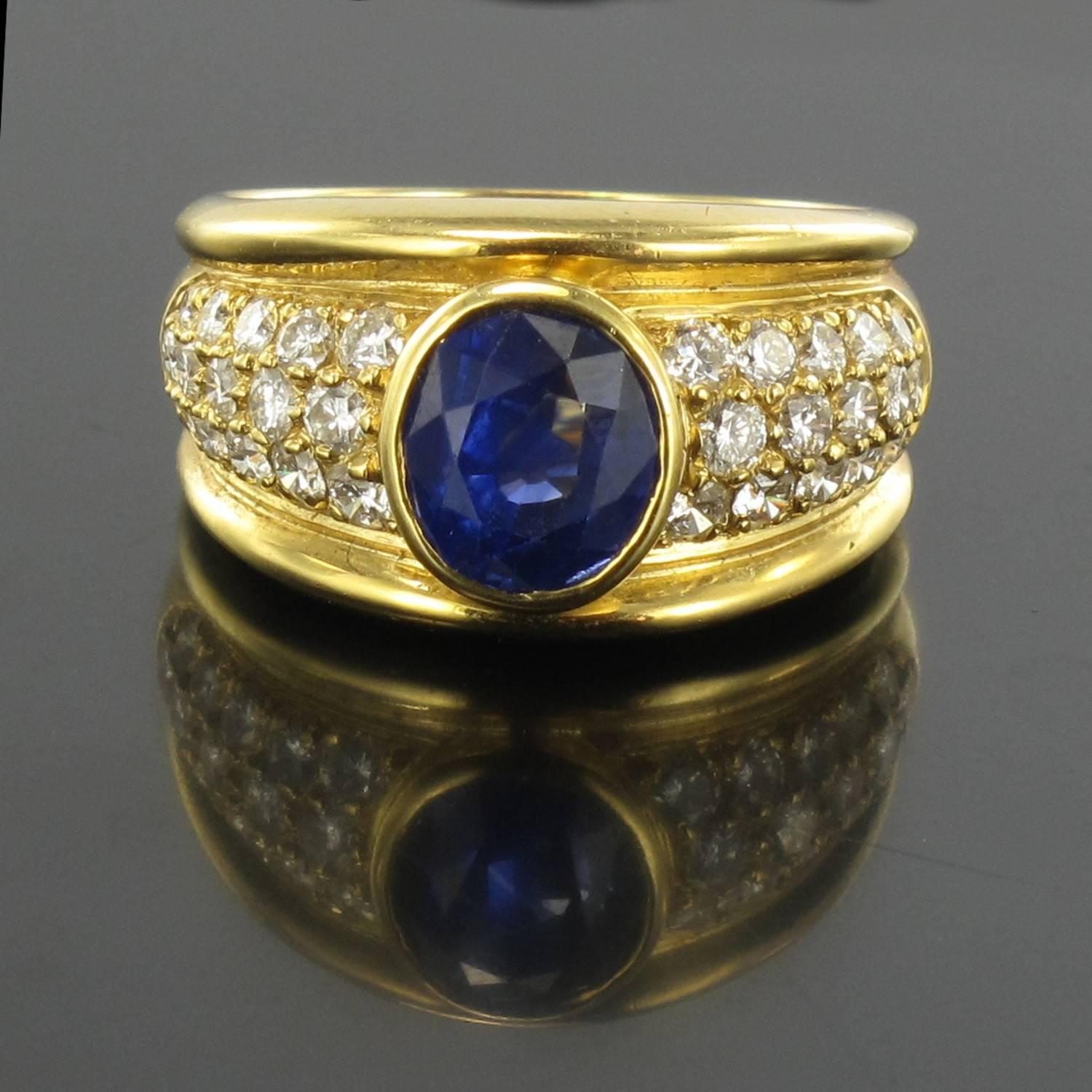 Ring in 18 carat yellow gold, eagle head hallmark. 
Bezel set with an oval blue sapphire surrounded by pave diamonds. The sapphire is an sublime deep and bright blue, an outstanding piece of jewellery. 
Total diamond weight: about 0.95 carat 
Total