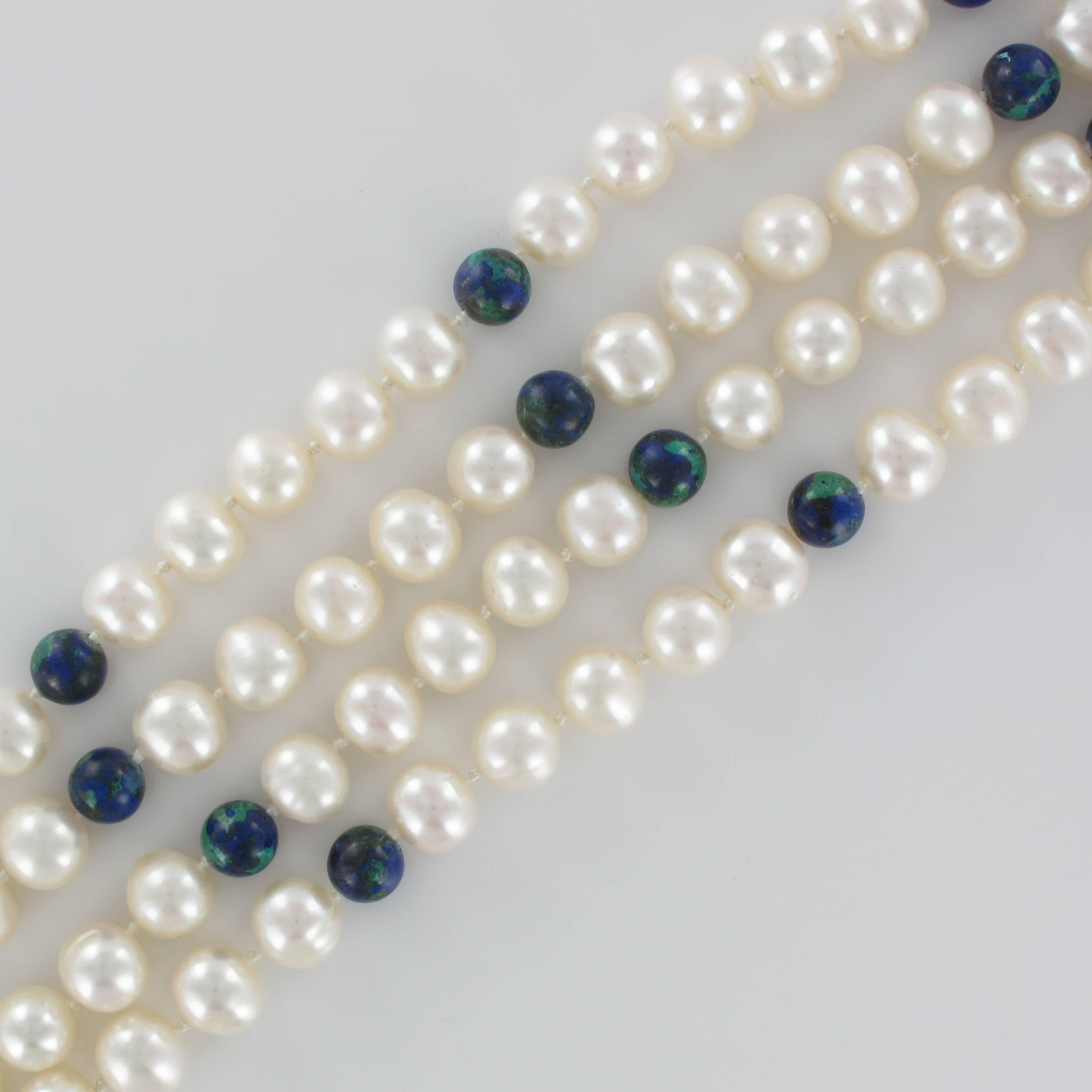 Long matinee necklace of 90 white oriental baroque cultured pearls separated at regular intervals by round azurite beads. 
The clasp is in 18 carat yellow gold.

Total length: 106 cm.
Bead diameter: 9 / 9.5 mm.
Total weight : about 120