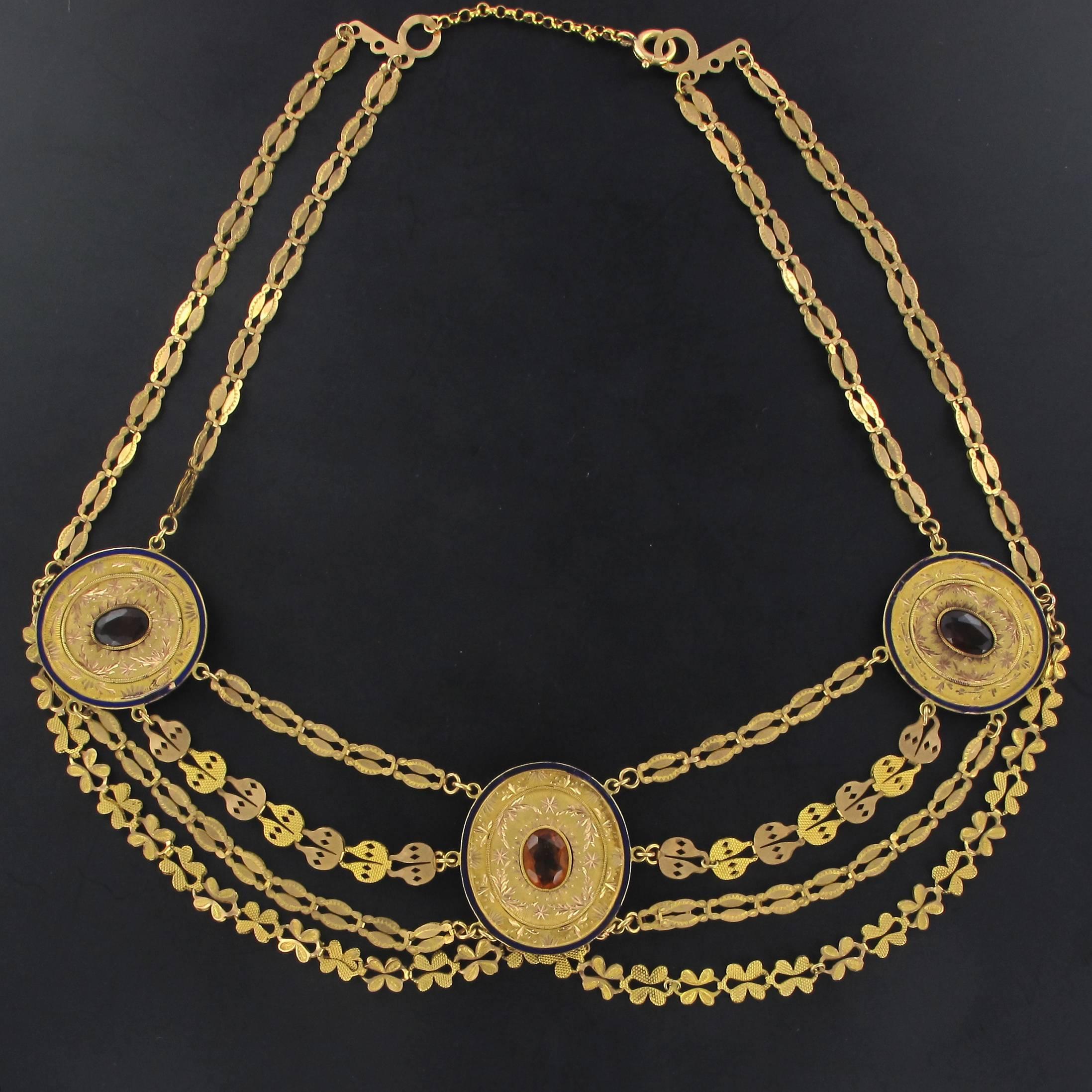 Necklace in 18 karat yellow gold. 
This rare antique golden necklace is composed of three finely engraved oval motifs, each is set with an oval yellow gem edged with a fine royal blue enamel border. These 3 motifs are separated and suspended at the