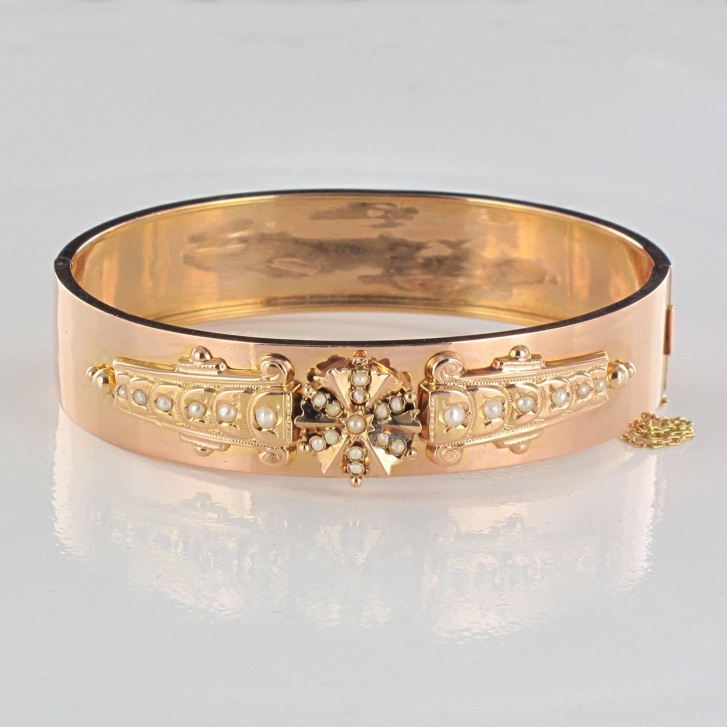 Bracelet in 18 carat rose gold 750 thousandths, eagle head hallmark.

Half oval ring, it is set on its top in aplique of a decoration set with half fine pearls. It opens with a ratchet hinge on the side and has a safety chain.

Circumference: