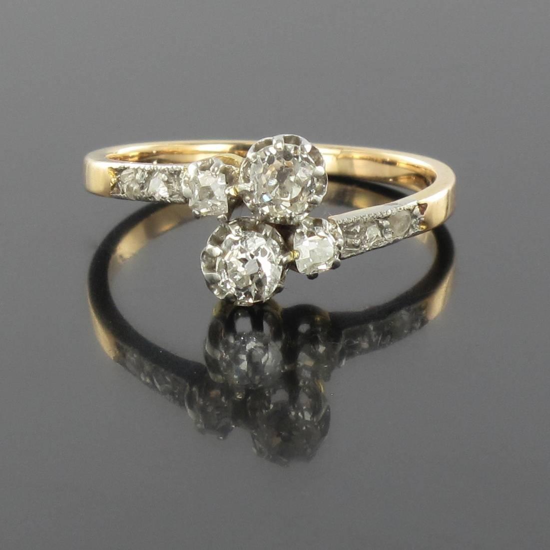 Ring in platinium and 18 carat yellow gold, eagle head hallmark. 

This delicate antique ring could be described as femininity incarnate. This Lovers ring is set with 2 cushion cut diamonds each with another smaller cushion cut diamond alongside.