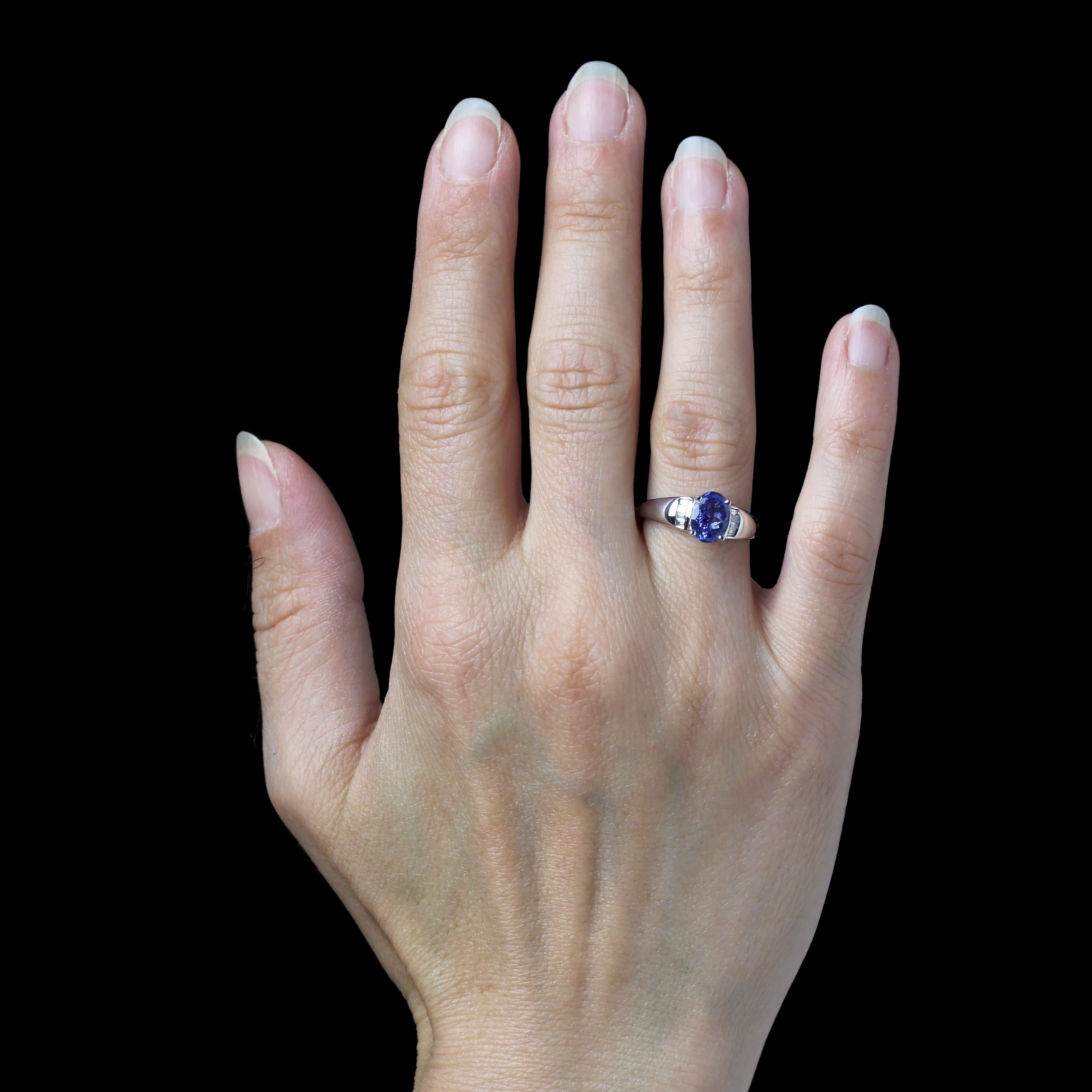 Anello in oro bianco 18 carati.
Questo moderno anello in oro bianco presenta una fascia a goccia ornata in cima da una tanzantite ovale incastonata con 4 griffe, sostenuta su entrambi i lati da 2x4 diamanti taglio baguette in una montatura a