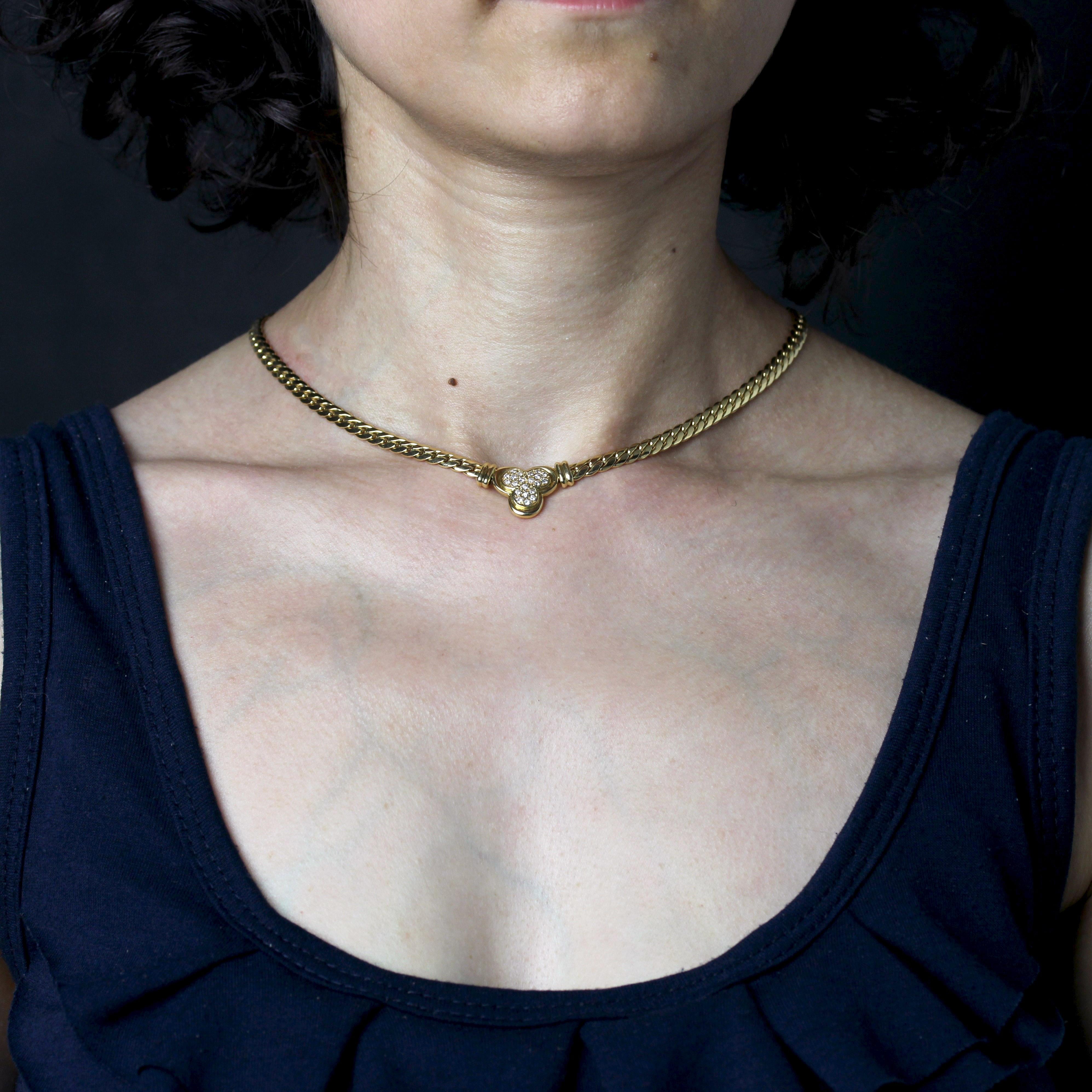 Collier en or jaune 18 carats, poinçon tête d'aigle.
Ce collier moderne en or jaune présente un maillon gourmette plat retenant un motif de trèfle à trois feuilles pavé de diamants modernes de taille brillant sur le devant. Le fermoir est un cliquet