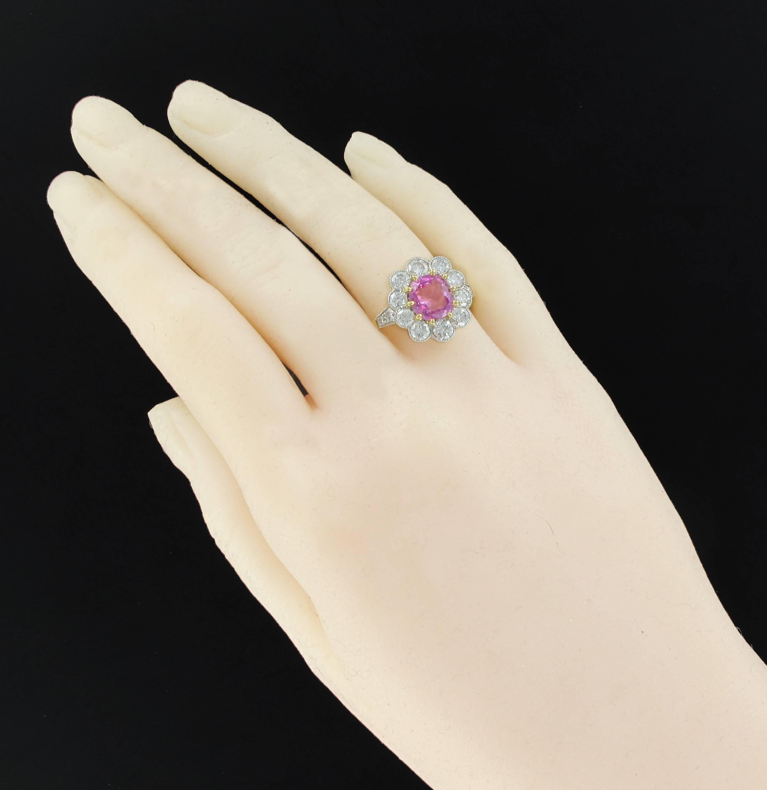 Ring in 18 carats yellow gold, eagle head hallmark and platinum, dog's head hallmark.
This beautiful daisy ring is set with claws of a cushion-cut pink sapphire surrounded by 10 brilliant-cut diamonds in millegrains set. On either side of the head
