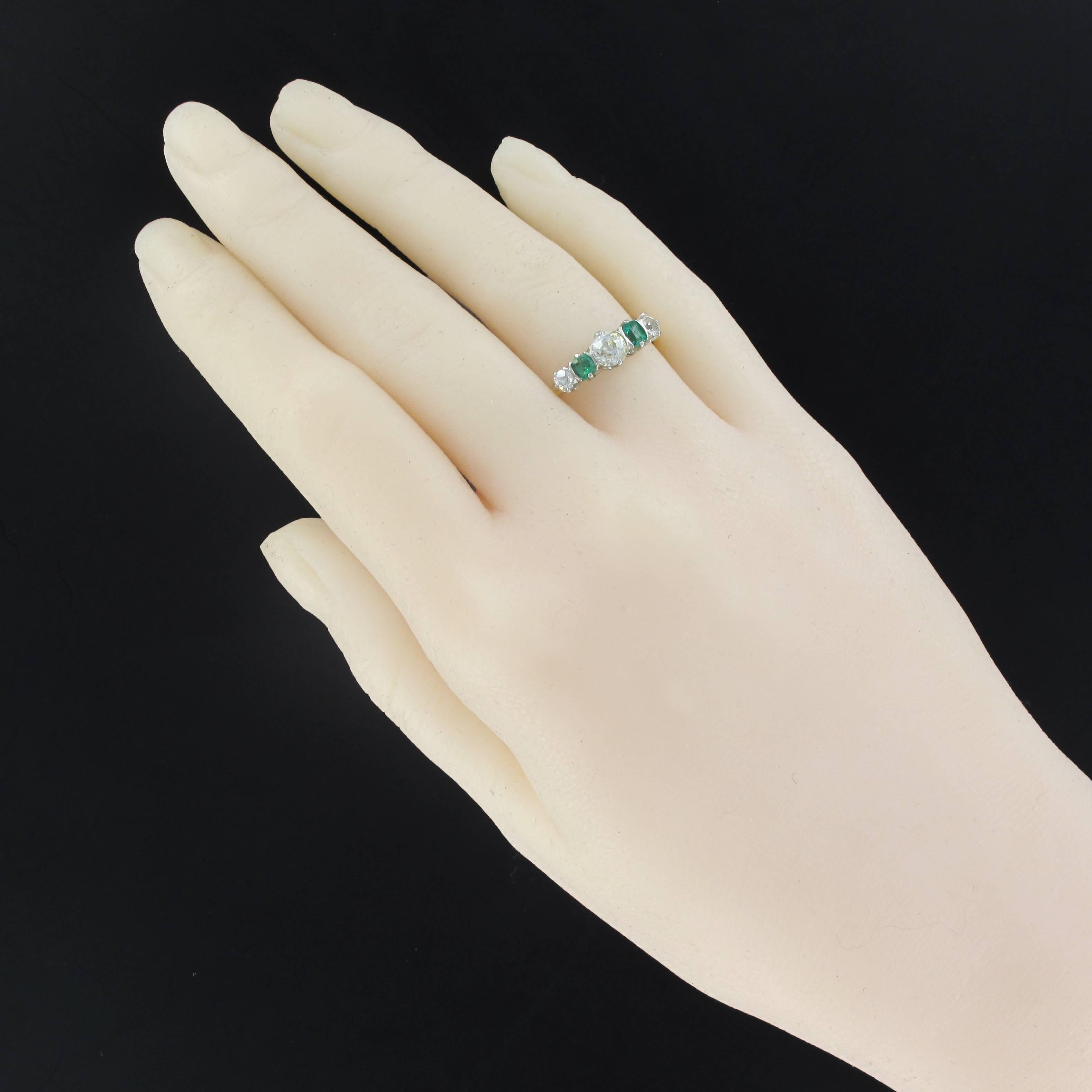Ring in 18 carats yellow gold and white gold, 750 thousandths.
This charming antique ring is set with claws of an antique brilliant cut diamond supported on both sides of 2 emerald set with claws each shoulder of an antique brilliant cut