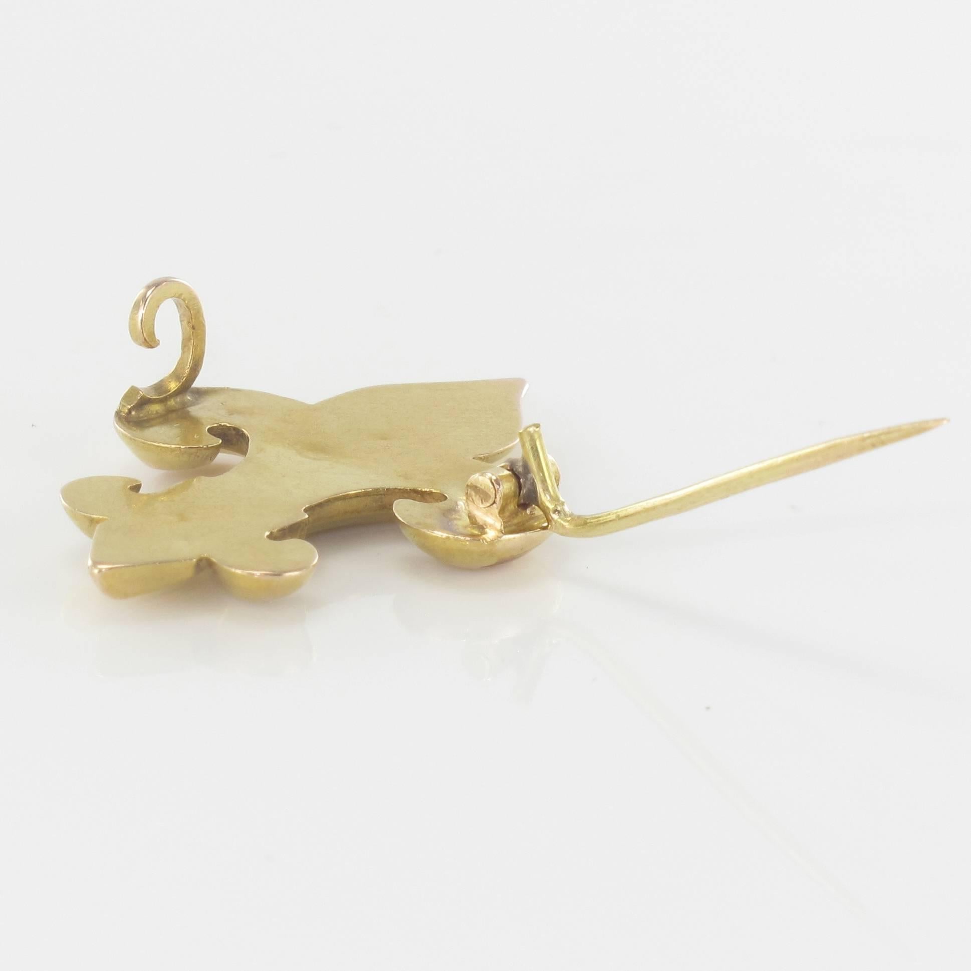 Brooch in 18 carats yellow gold, eagle's head hallmark.
It represents a fleur de lys tightened on the bottom by a gold link which is set with 3 half natural pearls. The clasp is a pin with safety hook.
Height: 3 cm, width 2.1 cm, widest thickness: