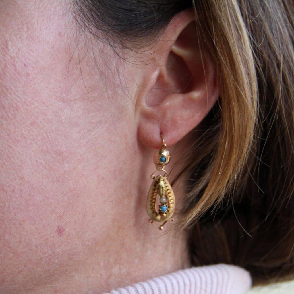 For pierced ears.
Earrings in 18 carats yellow gold.
Each pendant earring is set with a turquoise cabochon. A teardrop ear pendant, openwork is set with a green gold leaf, a half natural pearl and a turquoise cabochon on the sleeper. The clasp is on