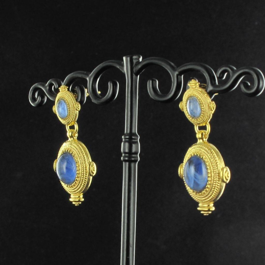 For pierced ears.
Pair of earrings in vermeil, silver and yellow gold.
Two oval motifs one below the other, are set with a blue cabochon stone and bordered with a braid.The clasps are butterfly. 
Overall length: 3,5 cm, width to the widest: 2