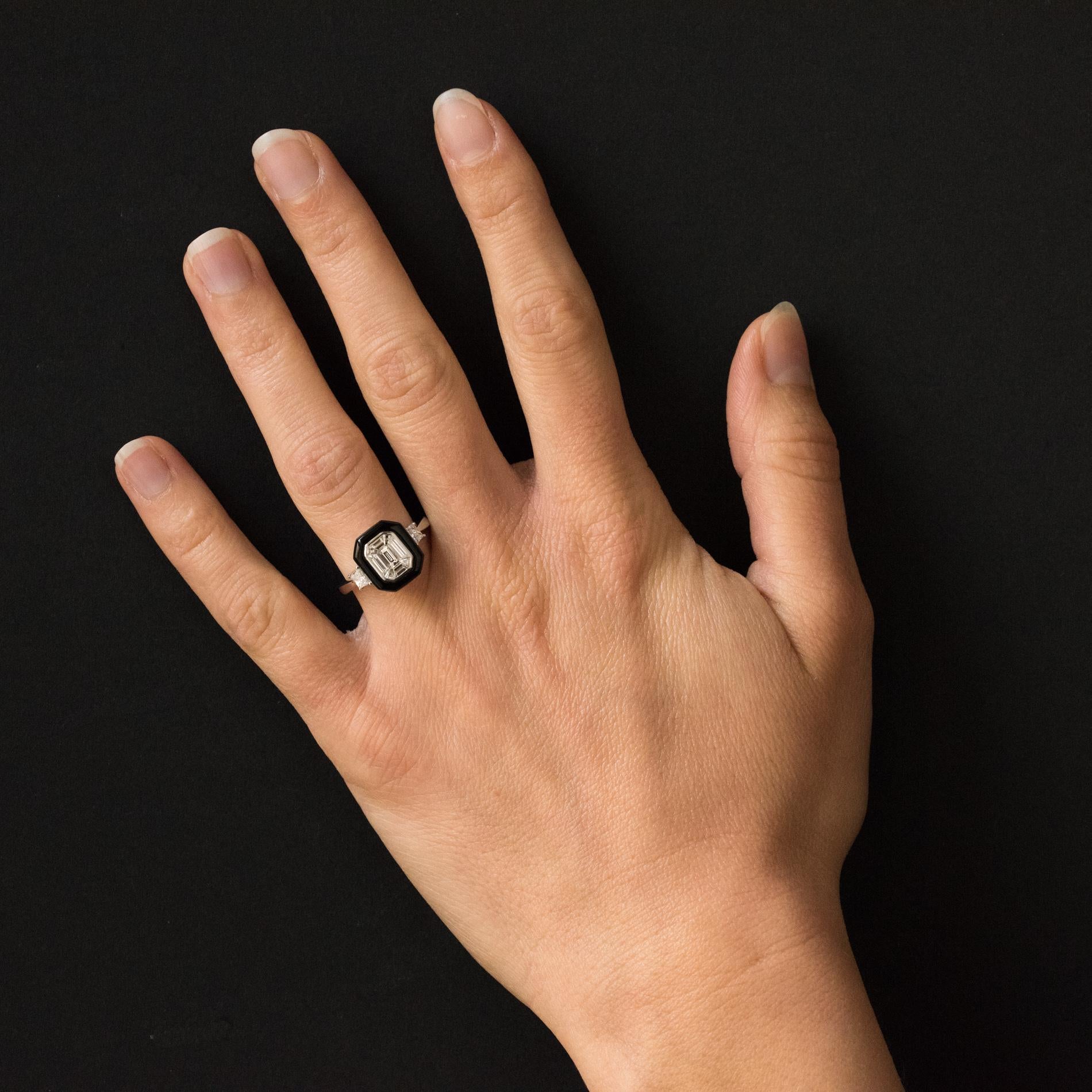 Ring in 18 ckarats white gold.
Splendid diamond ring art deco style, it is set on a hexagonal setting of baguette diamonds in a black agate entourage. On either side on the start of the ring are set bright modern- cut diamonds.
Total weight of