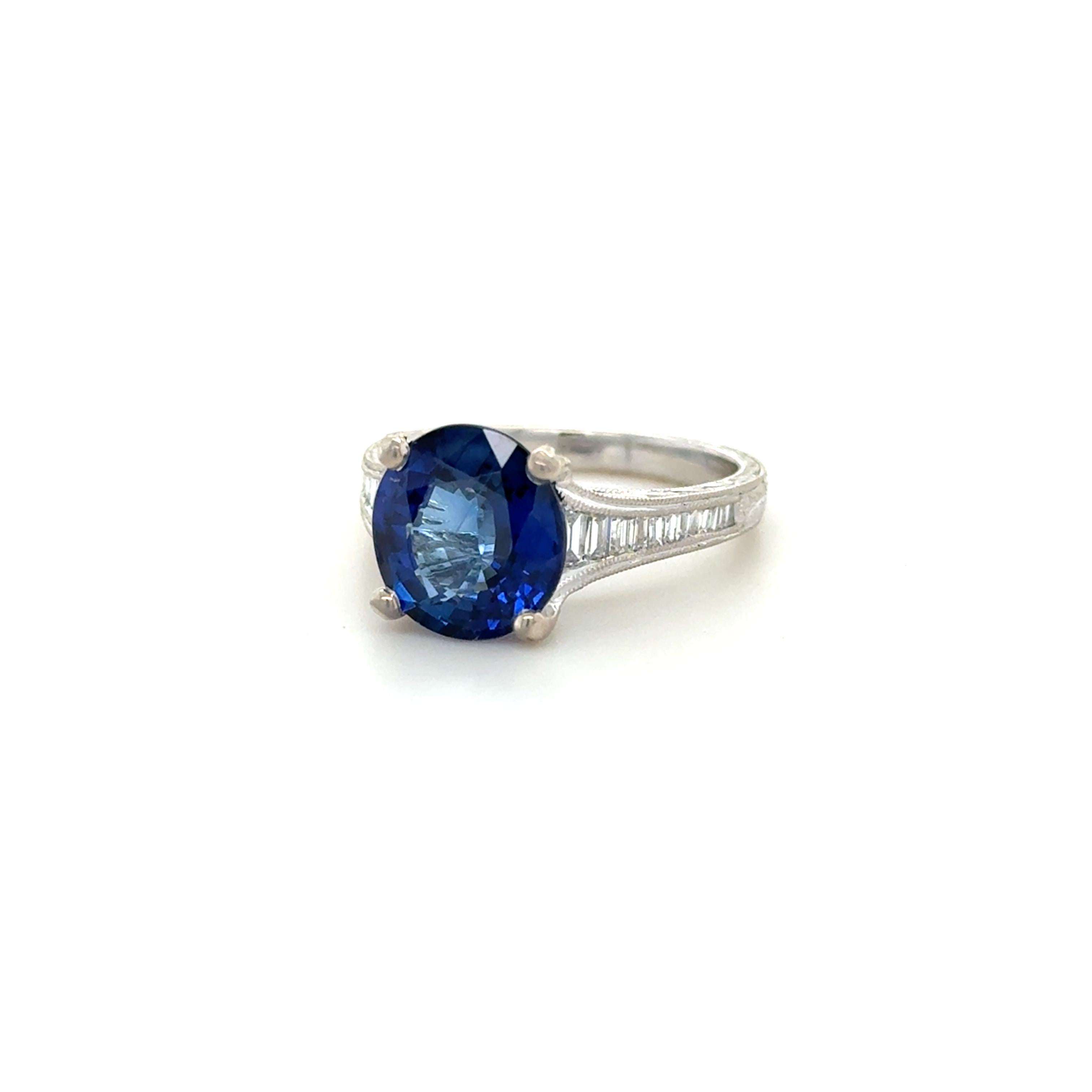 Questo splendido anello contiene uno zaffiro ovale a taglio misto del peso di 4,056 carati e delle dimensioni di 10,03 x 9,22 x 4,93 mm, affiancato da diamanti a taglio baguette lungo la fascia del peso totale di circa 0,50 carati. Con i dettagli