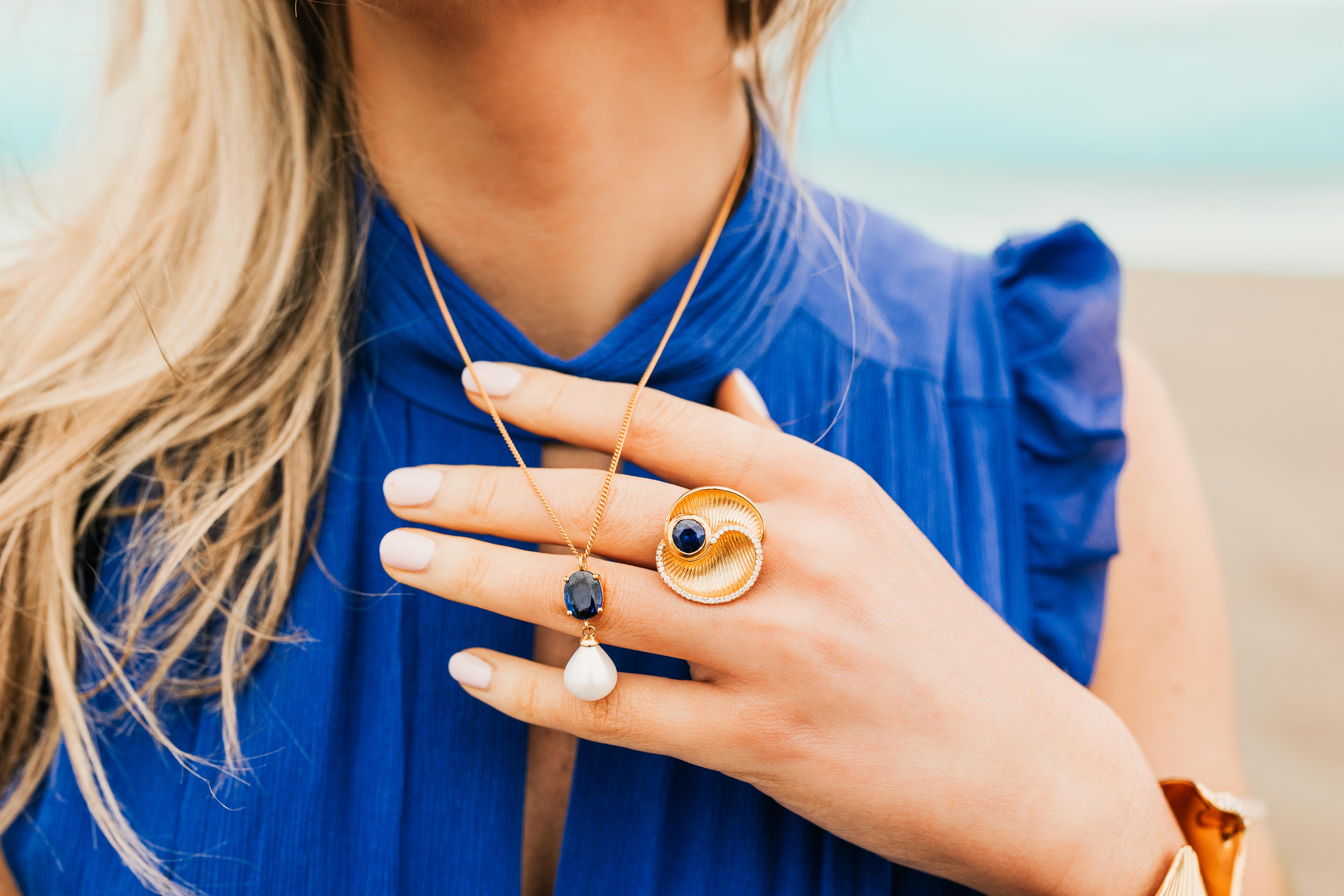 Notre nouvelle bague de cocktail inspirée de Santorini capture merveilleusement la beauté de l'île égéenne. Avec un chaton de disthène rond serti à l'intérieur d'une coquille d'or, avec un magnifique bord de diamants de laboratoire scintillants,