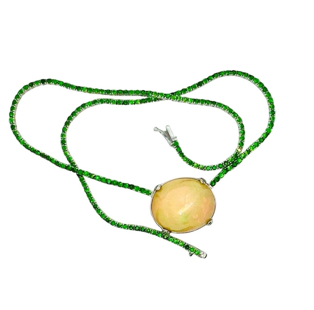 Questa incantevole collana è un pezzo unico, che unisce la bellezza eterea dell'Opale con il fascino ricco e verdeggiante dei granati di tsavorite. L'ipnotico Opale Etiope al centro, con i suoi caleidoscopici lampi di colore che si spostano e