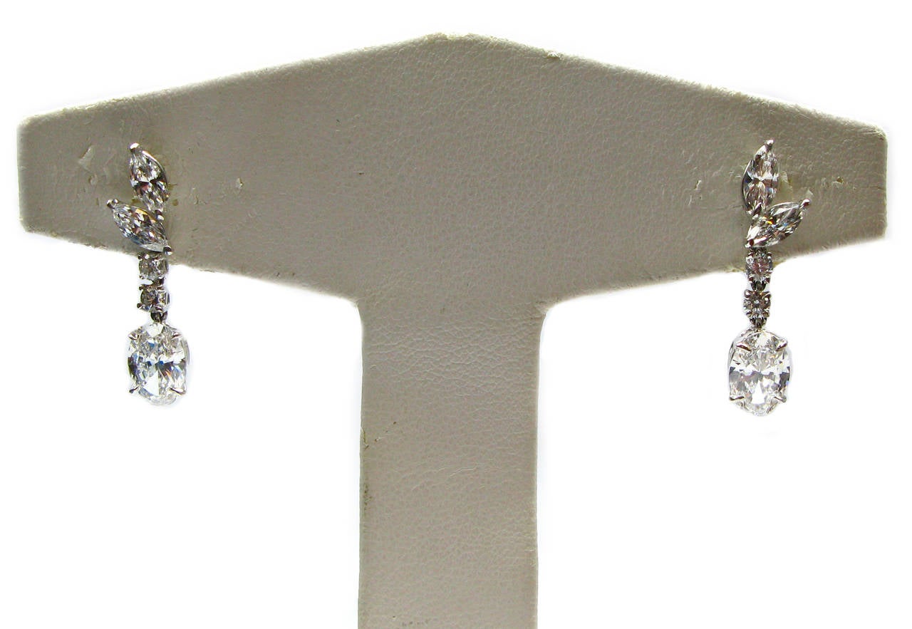 This stunning pair of handmade 18kt white gold drop earrings features two GIA certified oval cut diamond drops. One stone is a 1.02 carat, F color, VS2 clarity and the other is a 1.03 carat, F color, VS2 clarity. These stones are suspended from