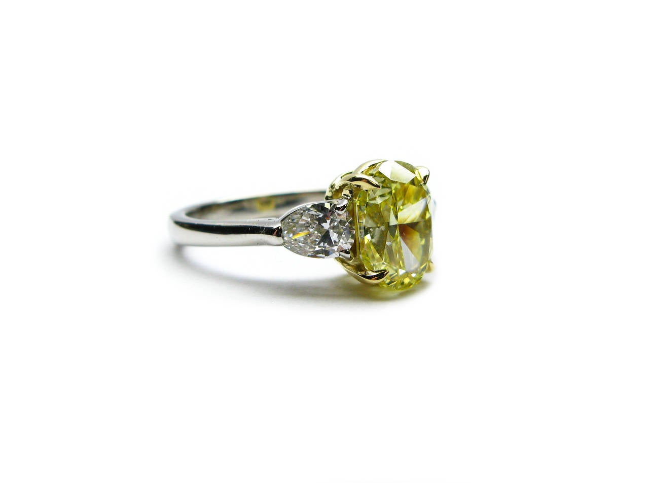 This GIA certified 2.50 carat Fancy Intense Yellow color SI1 clarity Oval cut diamond is set in a platinum and 18kt yellow gold ring in between two pear shape diamonds totaling 0.68ctw. This ring is sure to add subtle elegance to any outfit.