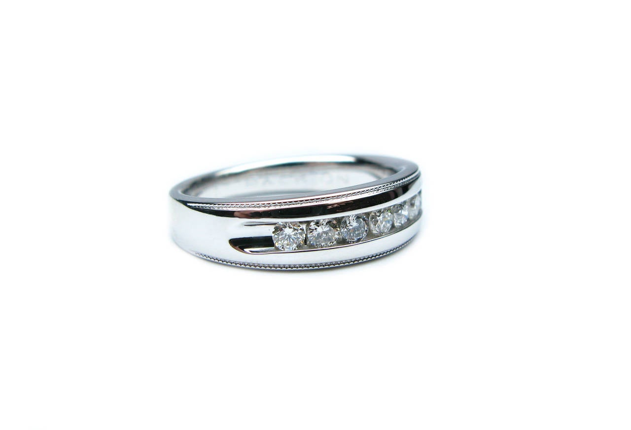 This simple, yet elegant 14kt white gold men's polished wedding band features 7 round brilliant channel set diamonds weighing approximately 0.50ctw with milgrain edges to complete the look.