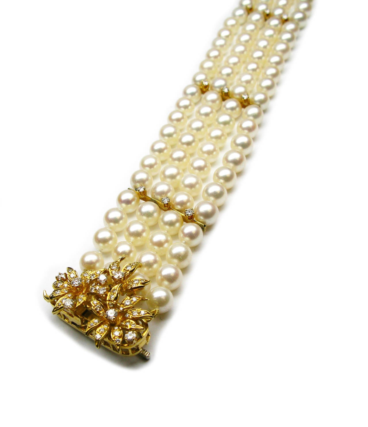 This stunning one-of-a-kind 18kt yellow gold bracelet is part of the Kurt Wayne collection. It features four strands of 6.5mm cream colored cultured pearls with three diamond accented bars and a spectacular diamond encrusted flower clasp with