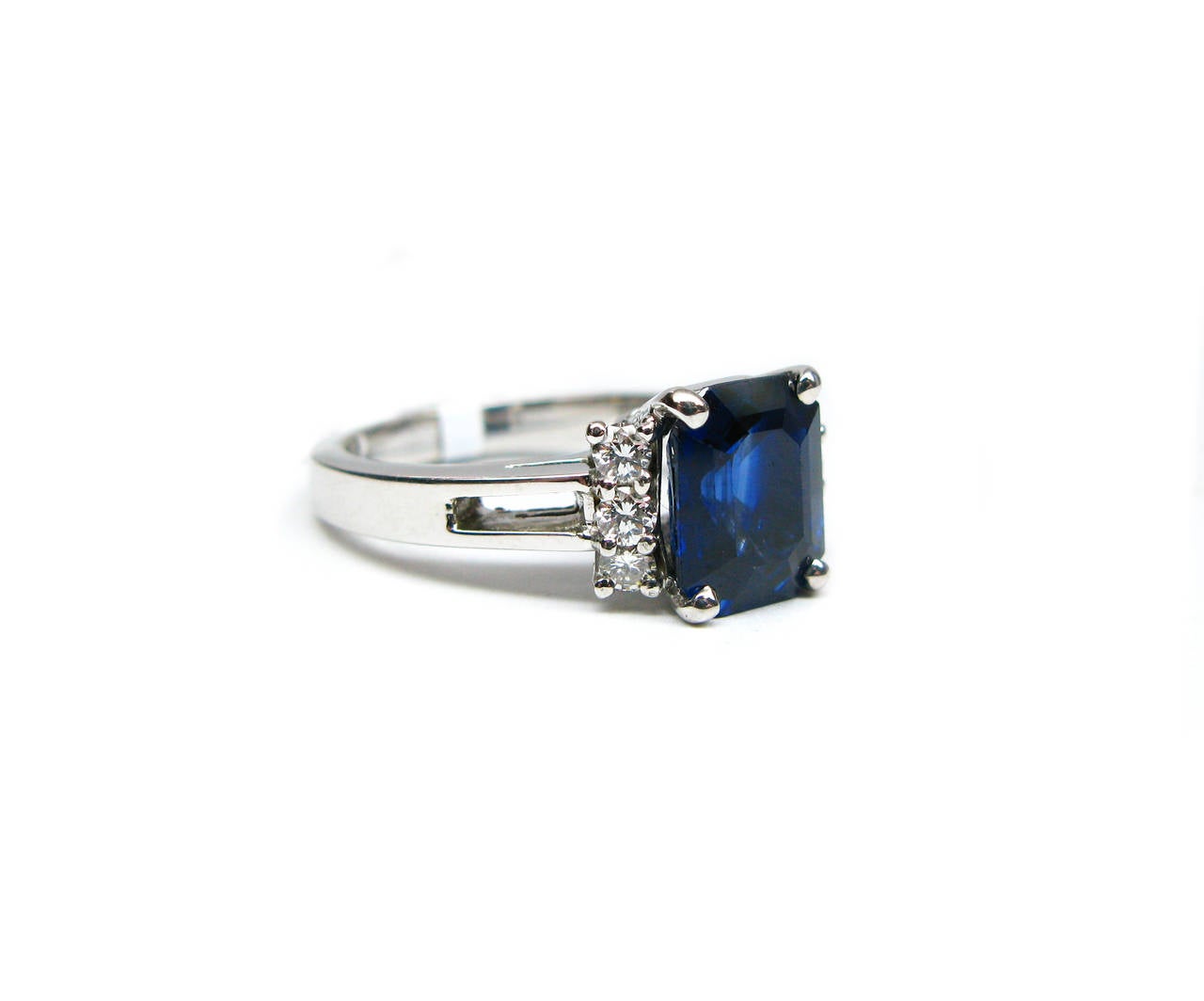 This classic ring is part of the Kurt Wayne collection. This 18kt gold ring features  a 3.15ct rectangular step cut deep blue sapphire center with six round brilliant diamond sidestones weighing 0.24ctw. The perfect addition to your collection!