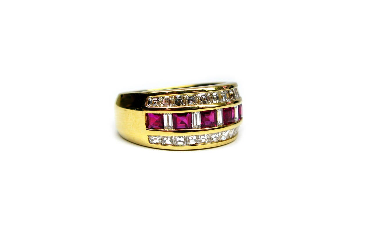 This gorgeous 18kt yellow gold band is part of the Kurt Wayne collection. It features six channel set princess cut ruby gemstones weighing 1.06ctw separated by five straight baguette diamonds weighing 0.25ctw. Two rows of channel set asscher cut