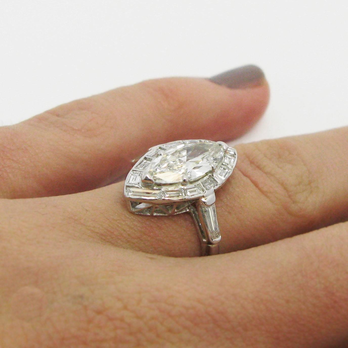 Im Mittelpunkt dieses wunderschön gestalteten Platinrings steht ein Diamant im Marquise-Schliff von 1::59 Karat mit der Farbe I und der Reinheit SI1. Der Marquise ist in eine elegante Baguettediamantenfassung eingefasst:: während zwei spitz