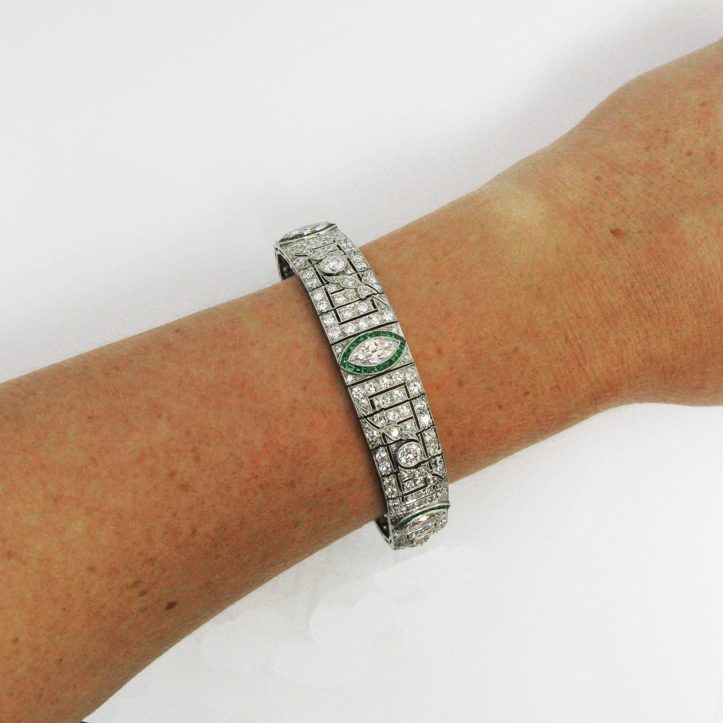 An elegant Art Deco platinum line bracelet features five graduated marquise-cut diamonds in square-cut emerald surrounds. Between each marquise diamond is a beautifully detailed, geometric plaque with a round-cut diamond bezel-set at the center of
