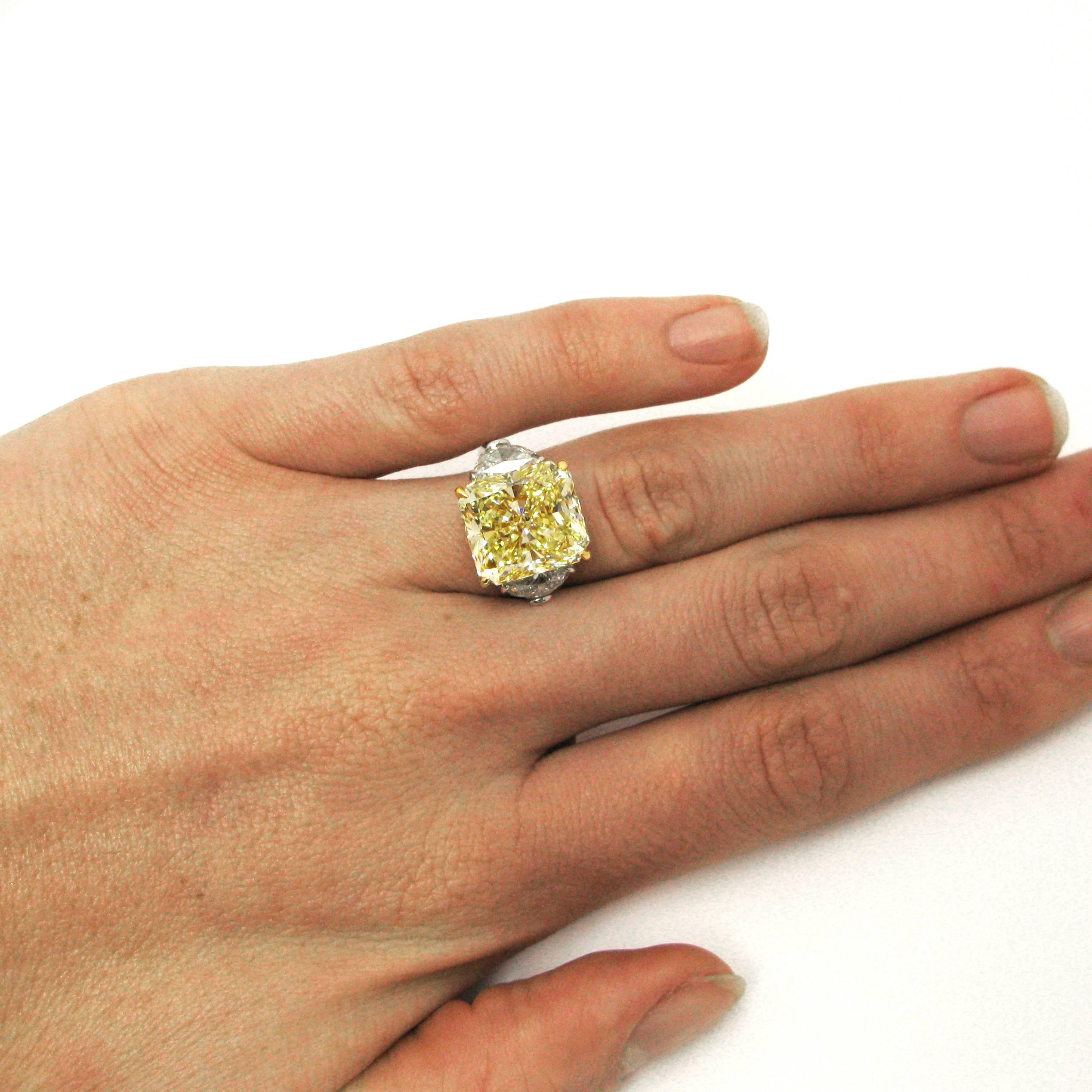 A stunning signed Harry Winston ring features a 10.01 carat Fancy Yellow radiant-cut diamond with VS1 clarity. This diamond is prong-set in an 18k yellow gold basket and flanked by two half-moon cut diamonds in platinum settings atop a platinum ring