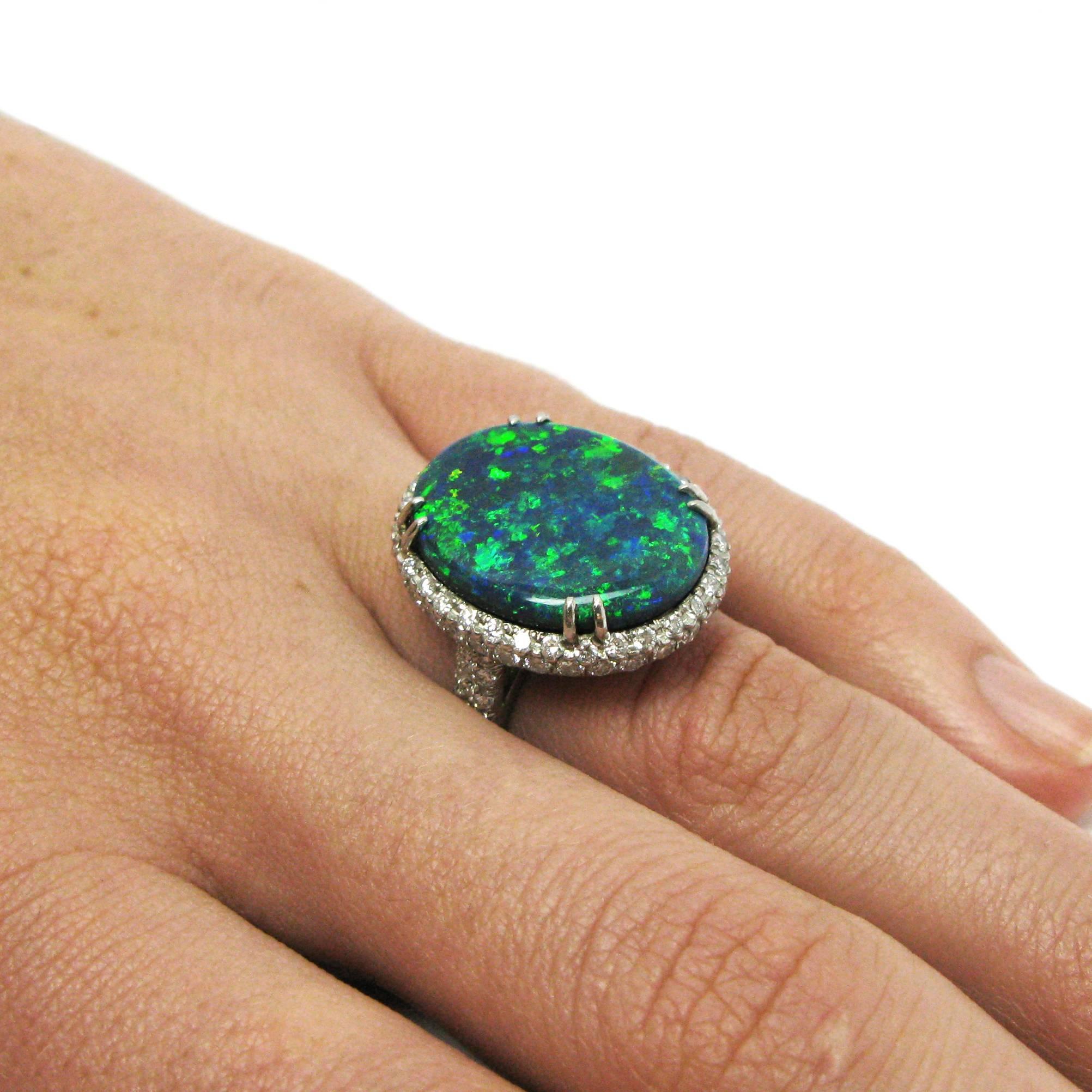 A spectacular ring by American designer Kurt Wayne centers around a jaw-dropping 11.50 carat blue opal with flashes of patchwork green and orange fire. This incredible stone is claw-set in a platinum mounting with 1.80 carats total of pave round-cut