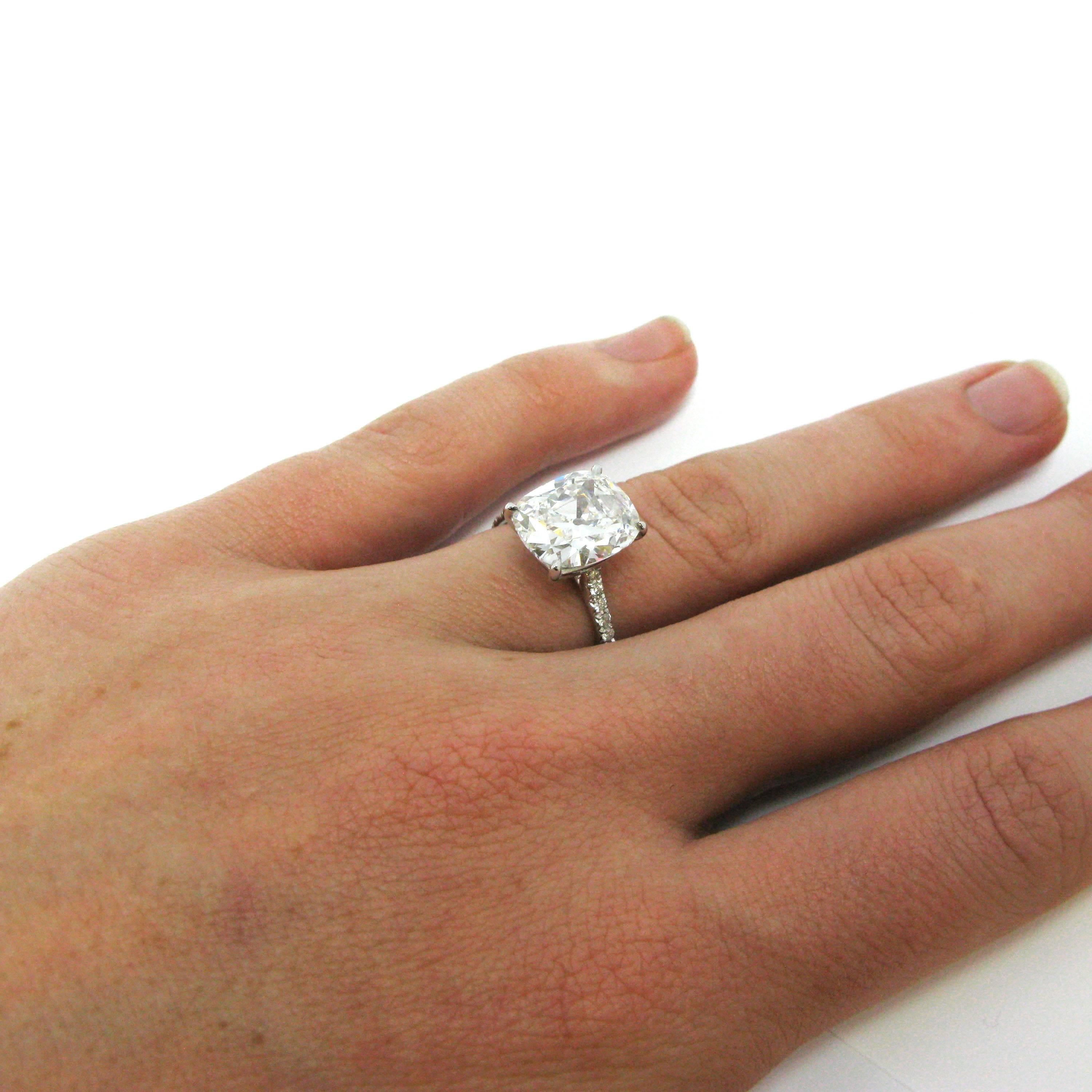 An elegant take on the classic solitaire engagement ring! A 4.15 carat cushion-cut diamond, with F color and VVS2 clarity, is prong-set into a simple platinum mounting set with 0.32 carat of pave diamonds down the sides of the ring shank. The large