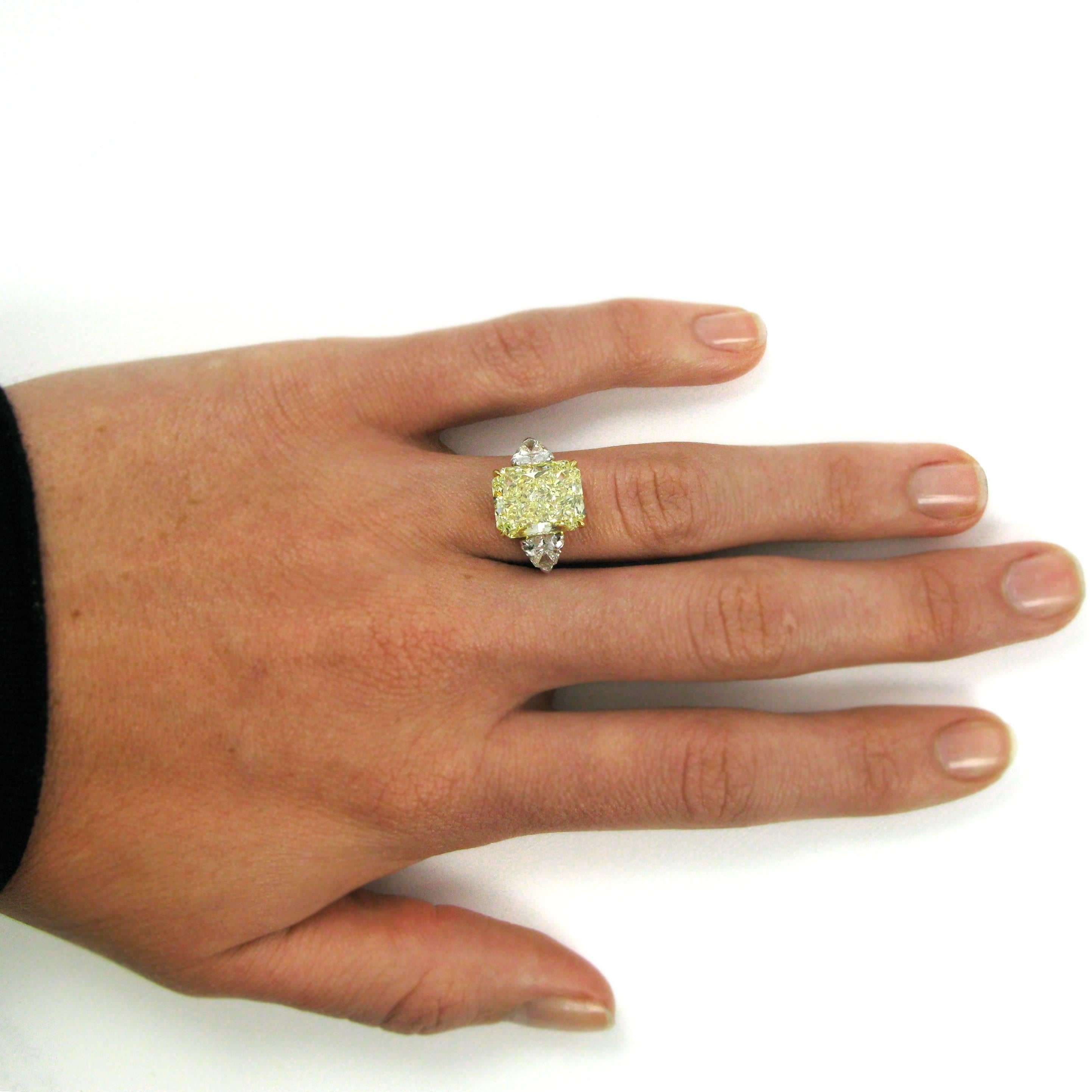 A lovely three-stone ring featuring a 7.17 carat sunshine-yellow Fancy radiant-cut diamond. The diamond is set in an 18k yellow gold basket and flanked by two shield-cut white diamonds totaling 1.62 carats, atop a platinum ring shank. 

Purchase