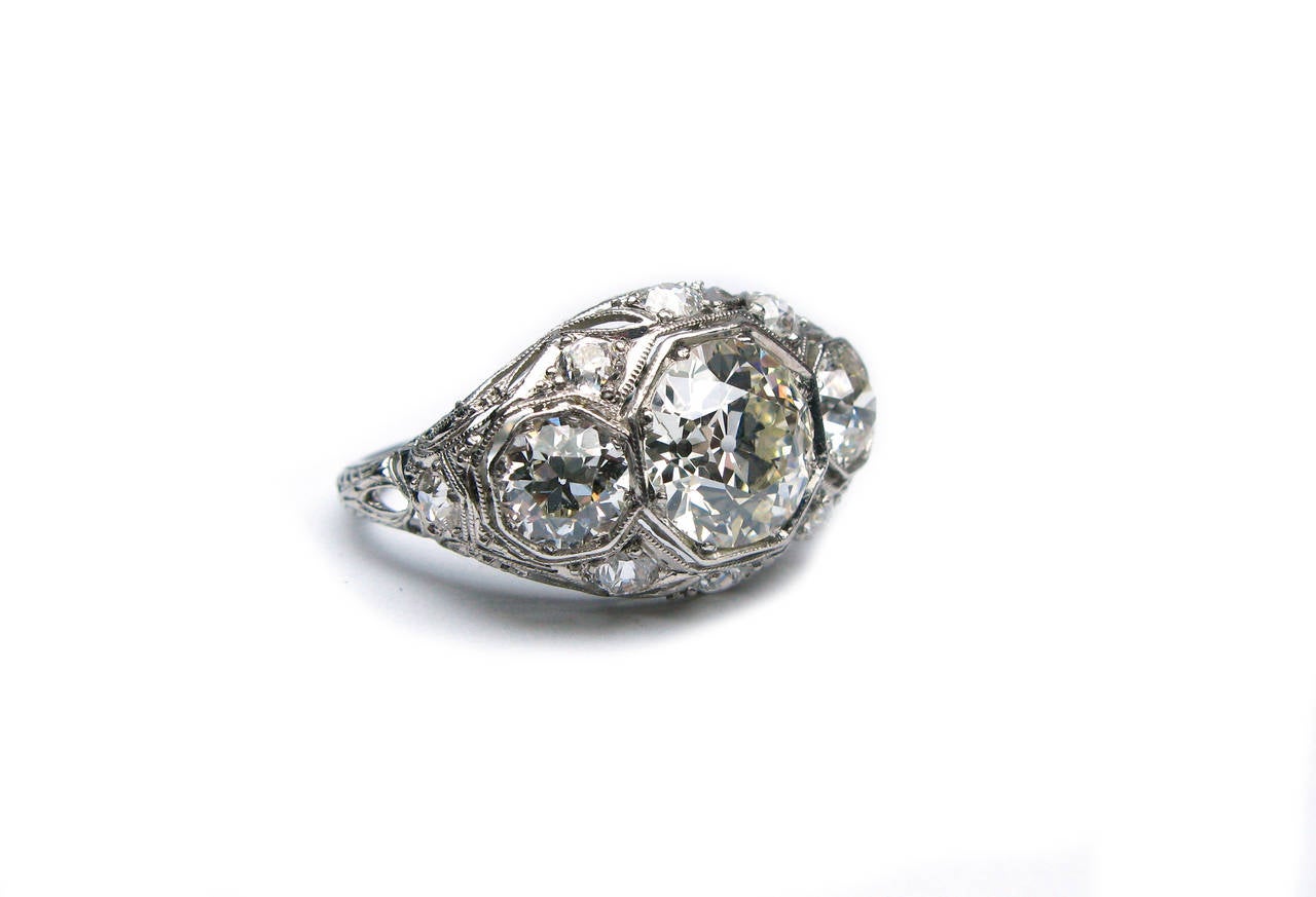 This beautiful Art Deco platinum ring features 8 high quality Old Mine Cut diamonds. The center diamond is estimated between 2.50- 3 carats and the two side diamonds are approximately .70ct each. This charming ring is one-of-a-kind and is sure to