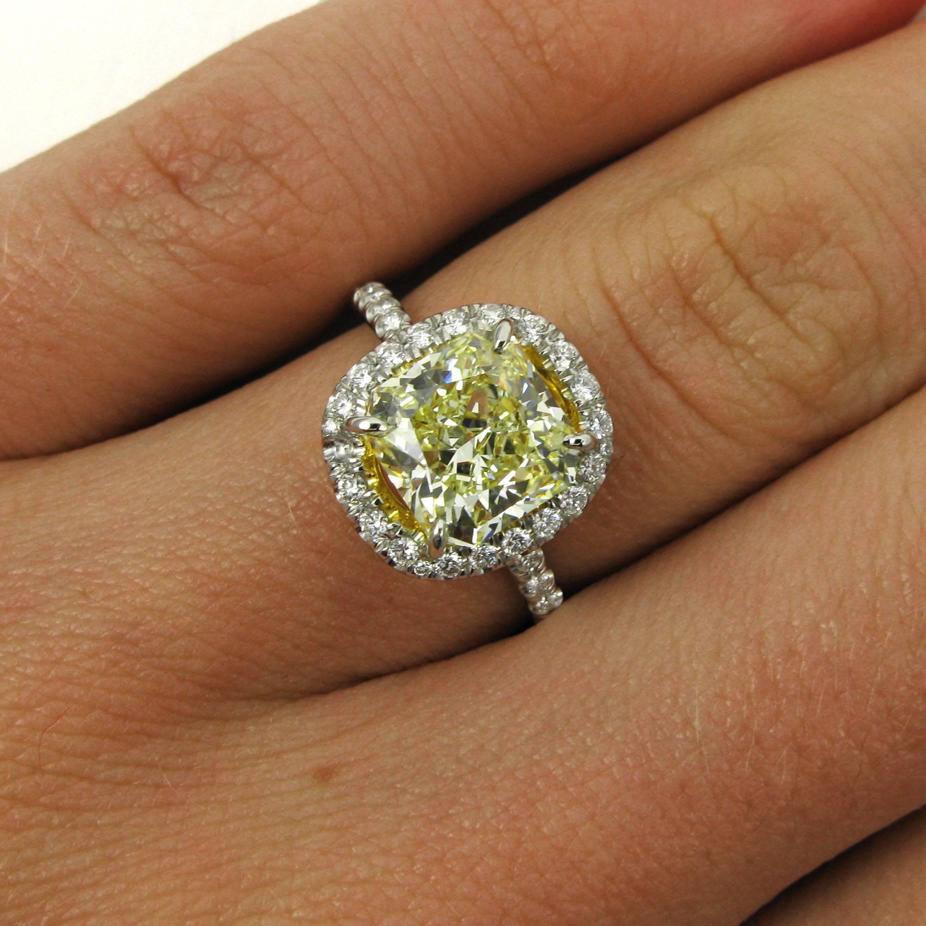This lovely ring centers on a 2.39 carat radiant-cut diamond with Fancy Light Yellow color and VS1 clarity. The diamond is set with 18k yellow gold prongs into a platinum halo frame ring studded with approx. 0.60 carat of pave white diamonds. 

This
