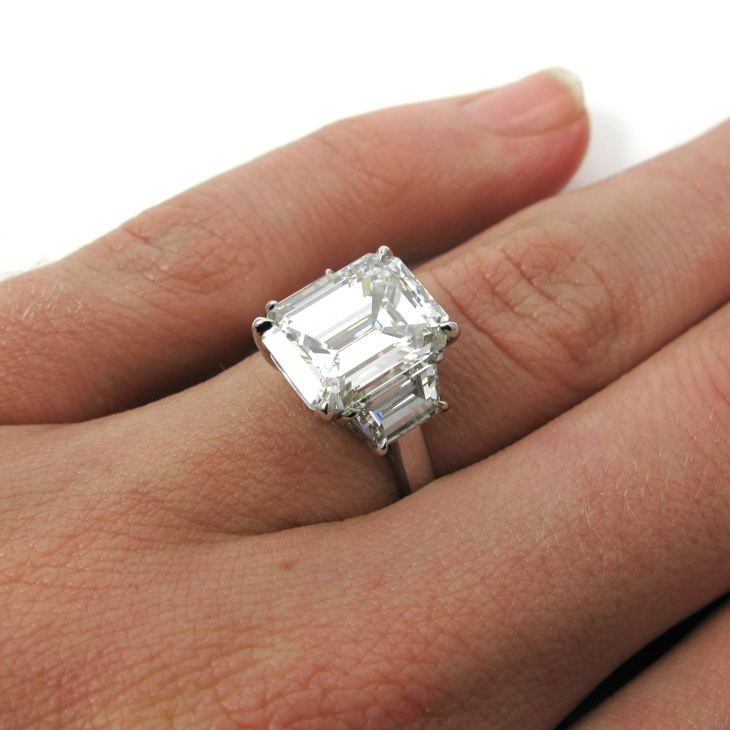 A GIA certified 4.77 carat emerald cut with I color and SI1 clarity is flanked by two trapezoid-cut diamonds totaling approx. 1.40 carats in this simple yet lovely platinum three stone ring. 

Purchase includes GIA Diamond Grading Report #5161038446